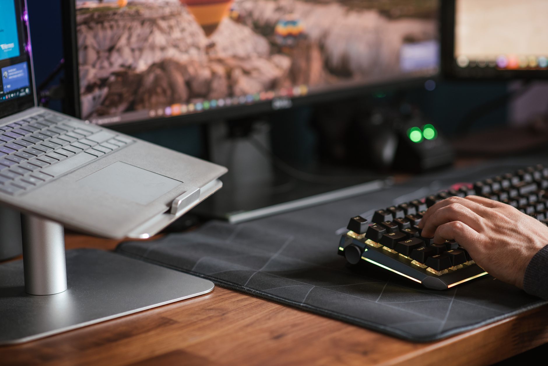 Crop anonymous male working on computer and typing on backlit keyboard placed