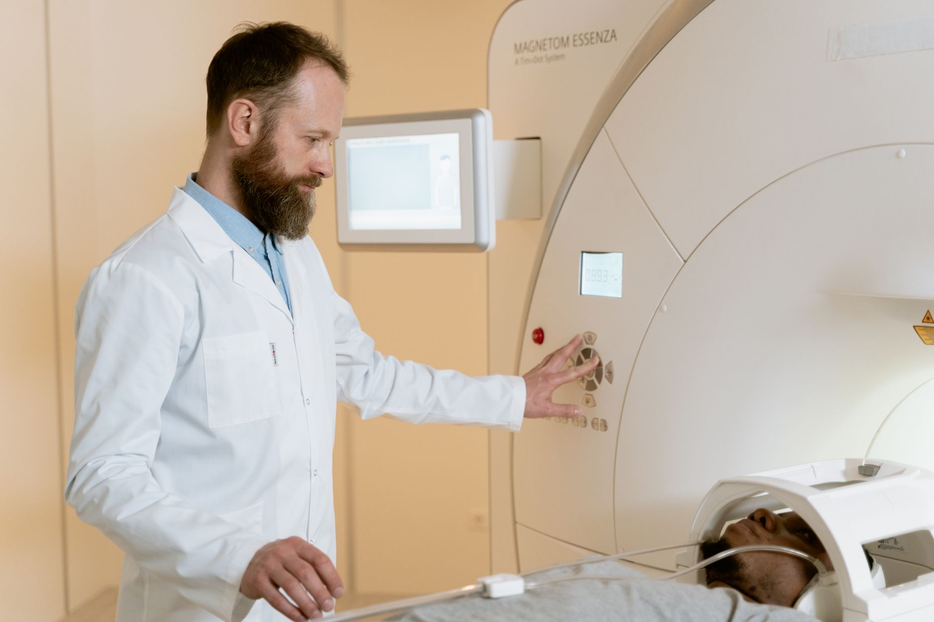 A doctor operates an MRI machine as a patient undergoes a scan