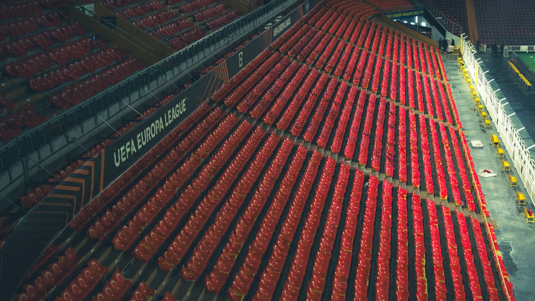 Rows of empty red seats in a UEFA Europa League stadium, captured