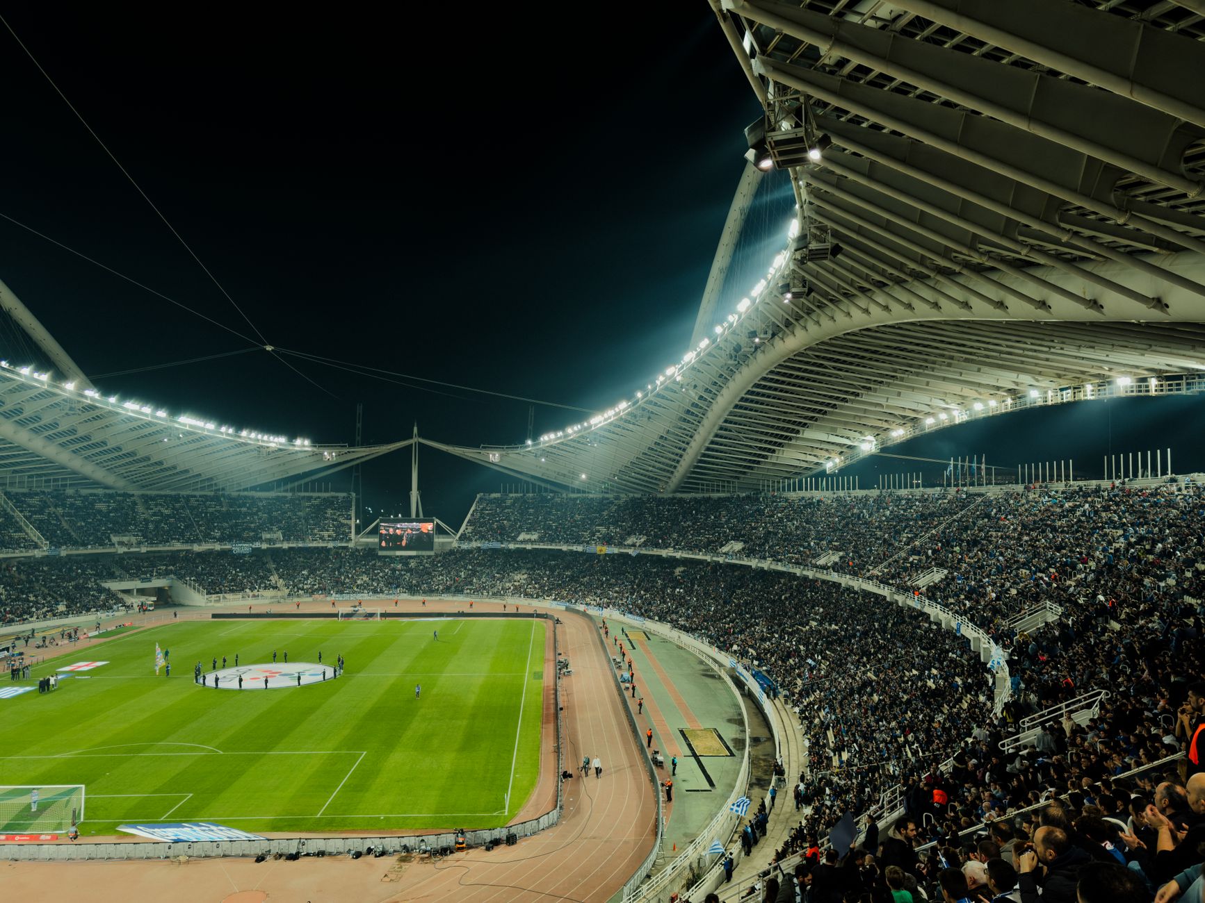 A crowded soccer stadium under bright lights at night, capturing the excitement