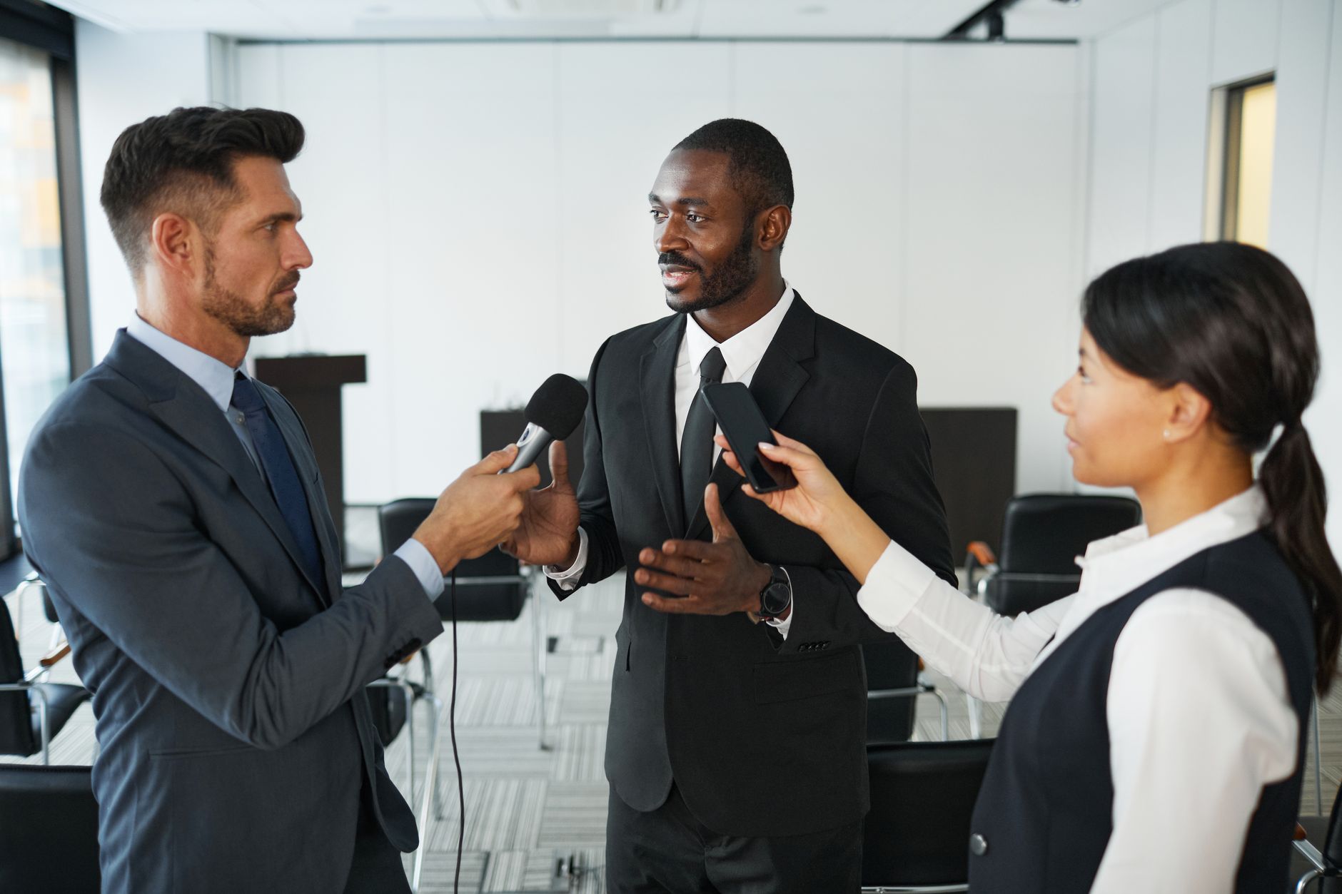 African American businessman in formal attire being interviewed by journalists with microphones
