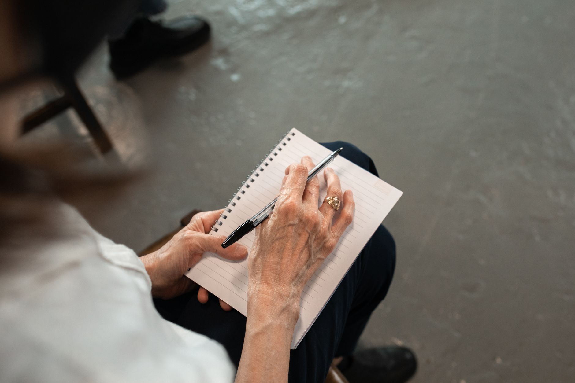 Close-up of senior hands with pen writing in a spiral notebook. Personal