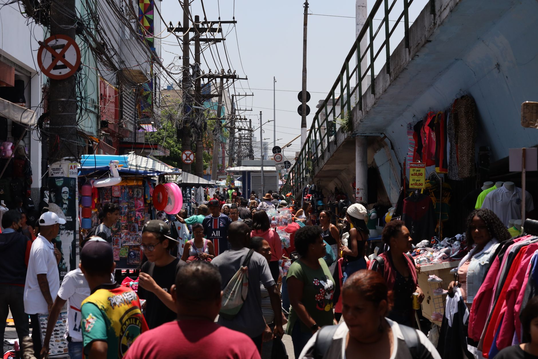 Crowded street market in São Paulo with diverse people and colorful stalls.