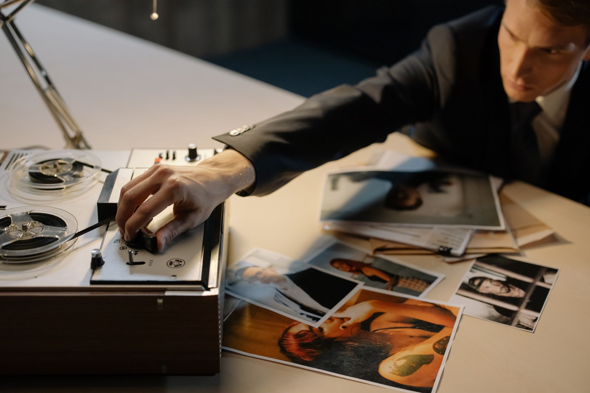 A detective adjusting a tape recorder during an investigation with photos spread