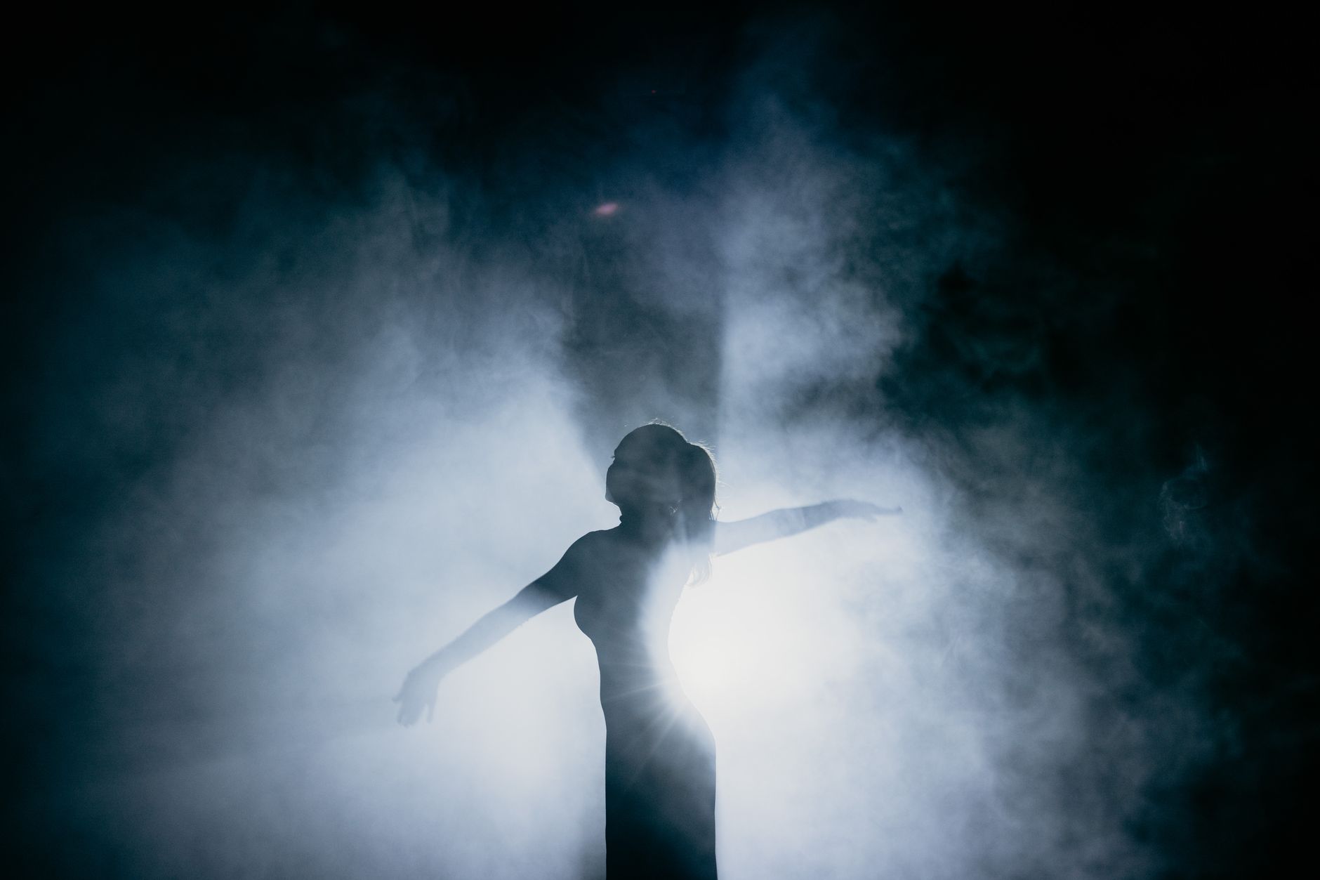 Captivating silhouette of a dancer gracefully posing amidst smoke, illuminated by dramatic