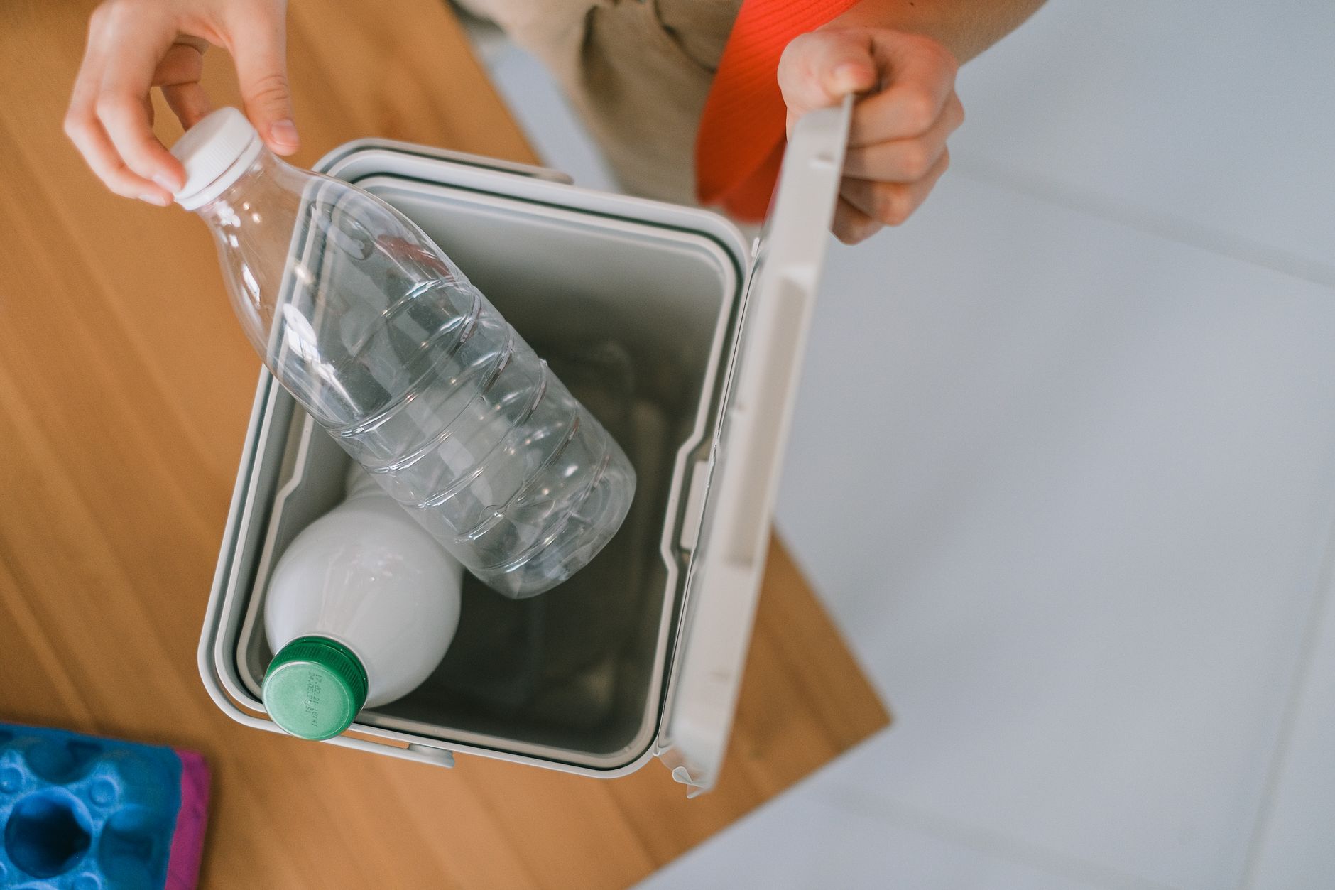 Top view of crop anonymous person opening container while disposing plastics bottle
