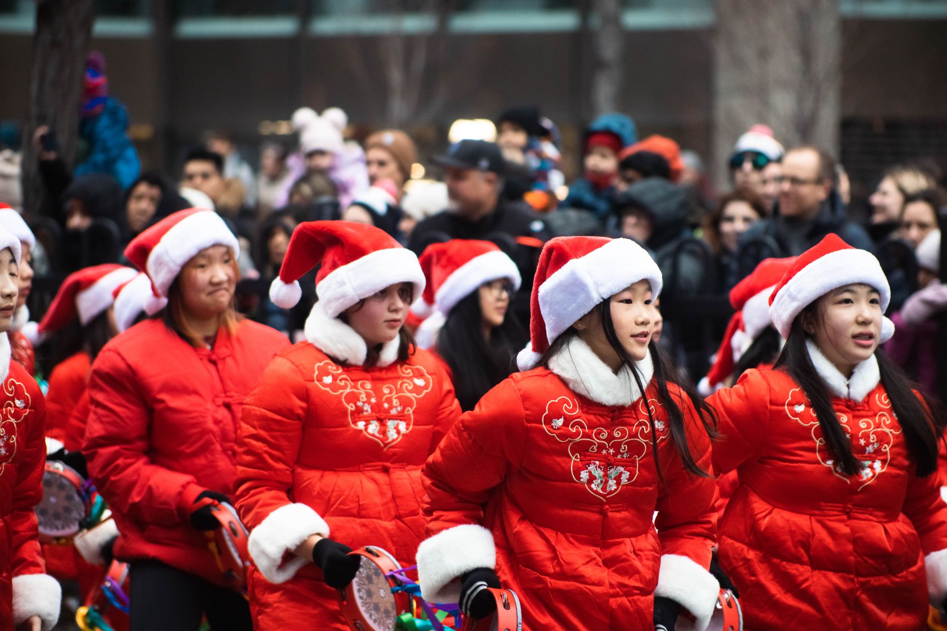 Young participants in a festive parade wearing Santa hats and red coats