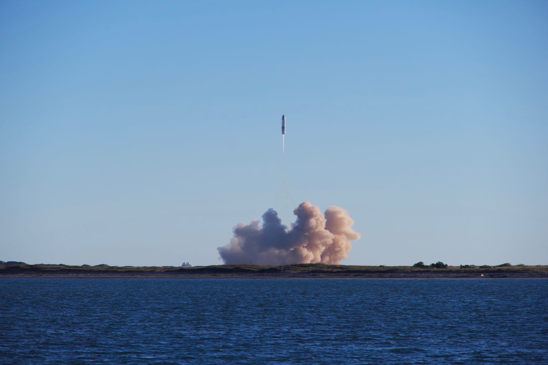 A rocket launch with smoke trails over South Padre Island, viewed across