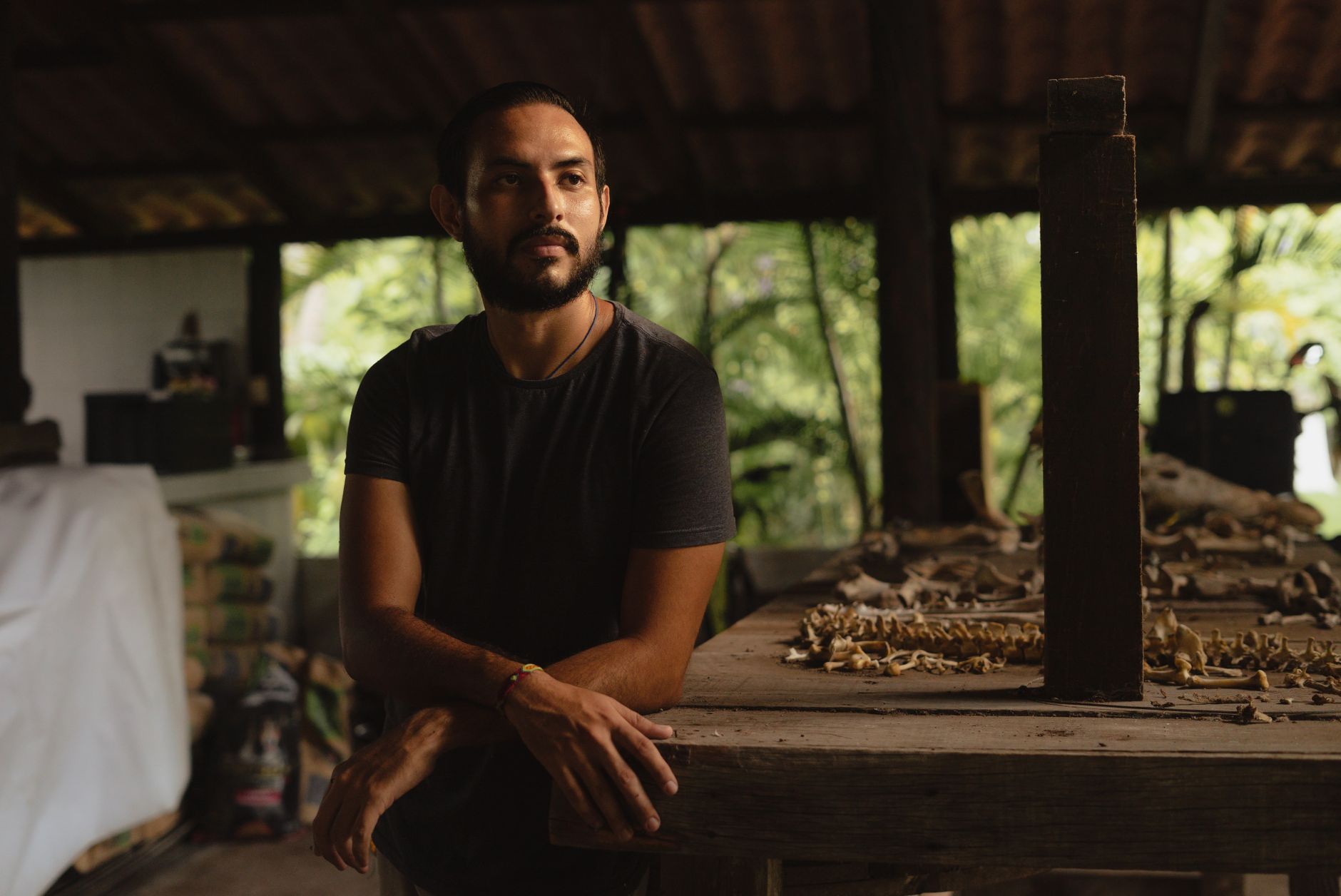 Man studying reptile skeleton in a rustic workshop with natural lighting.