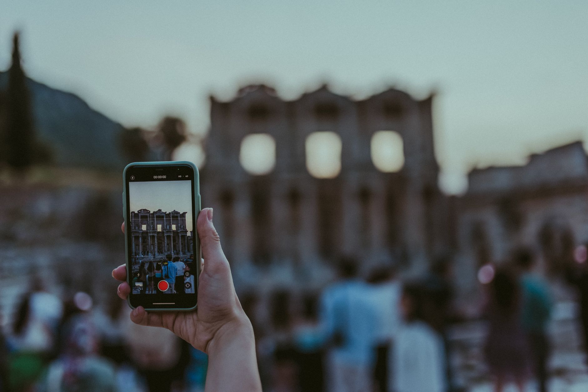 A blurred image of tourists photographing ancient ruins with a smartphone at
