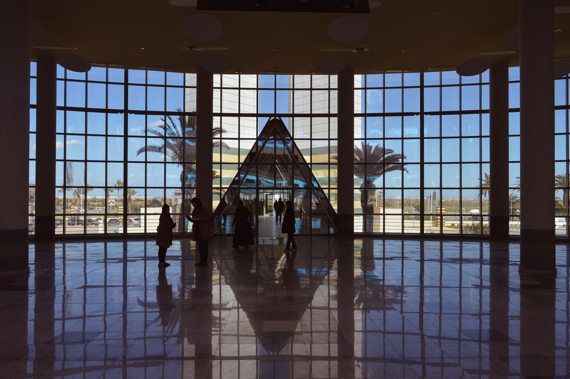 Interior view of a spacious lobby with a central glass pyramid and