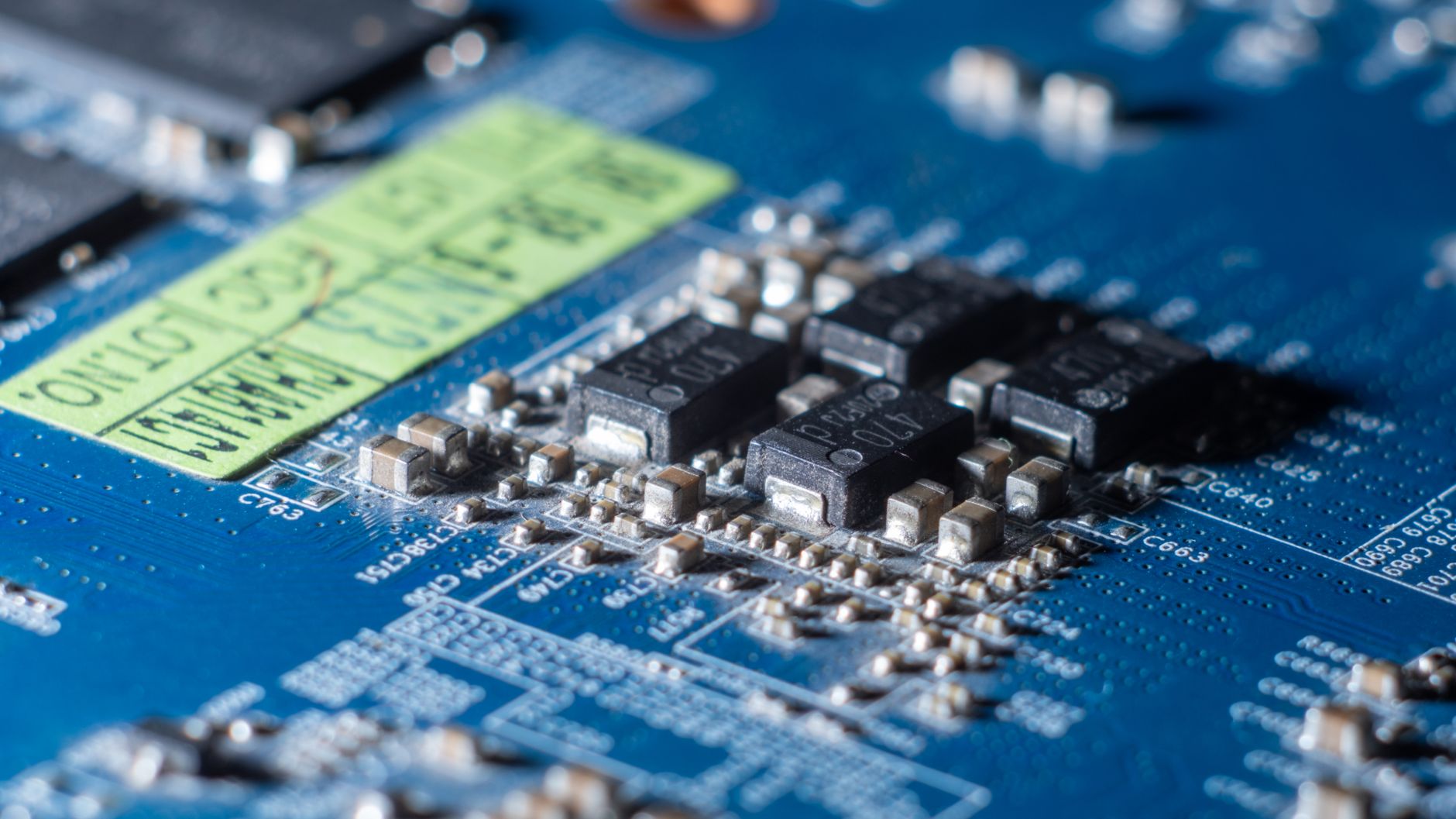 Detailed macro shot of a blue circuit board with multiple microchips and