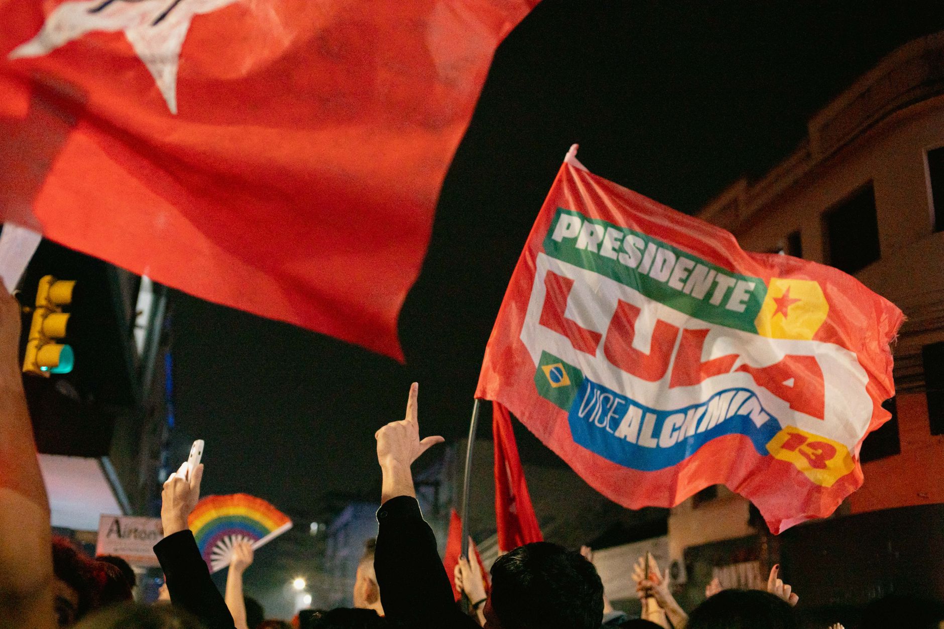 Supporters at a night rally waving flags with political slogans and hand