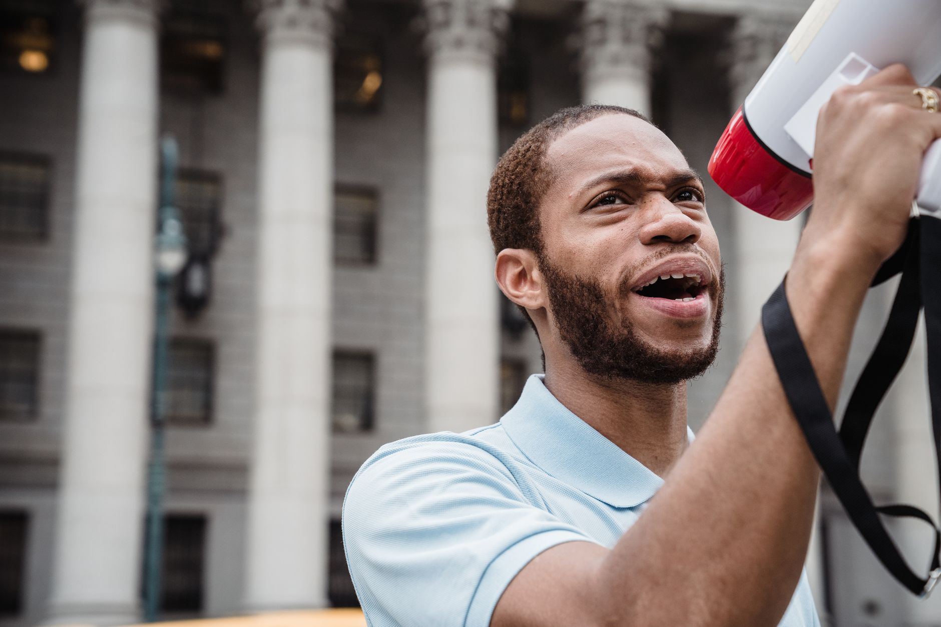 A passionate young activist speaks into a megaphone at a protest rally, advocating for social change.