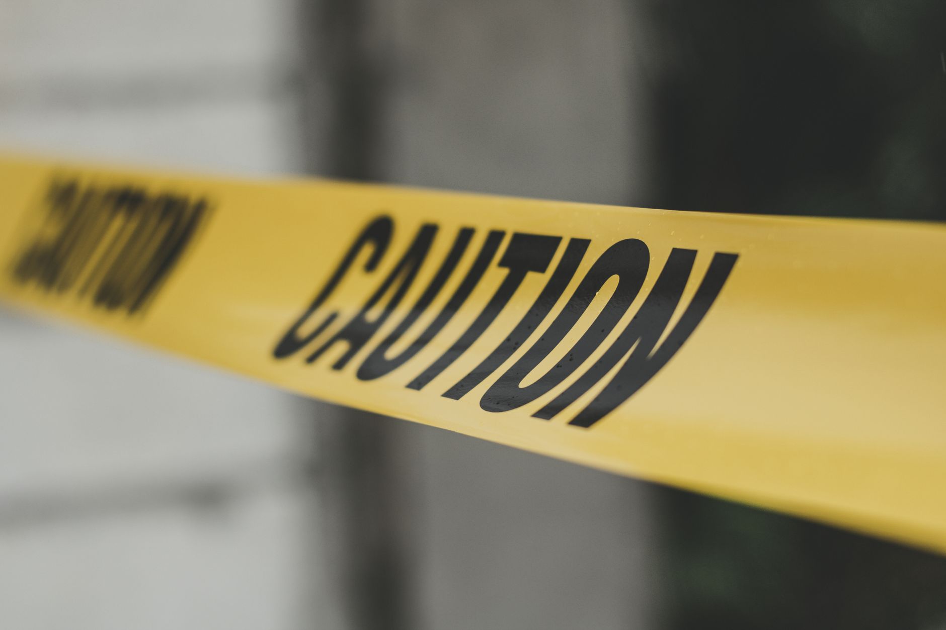 Close-up image of yellow caution tape with blurred background, emphasizing warning and