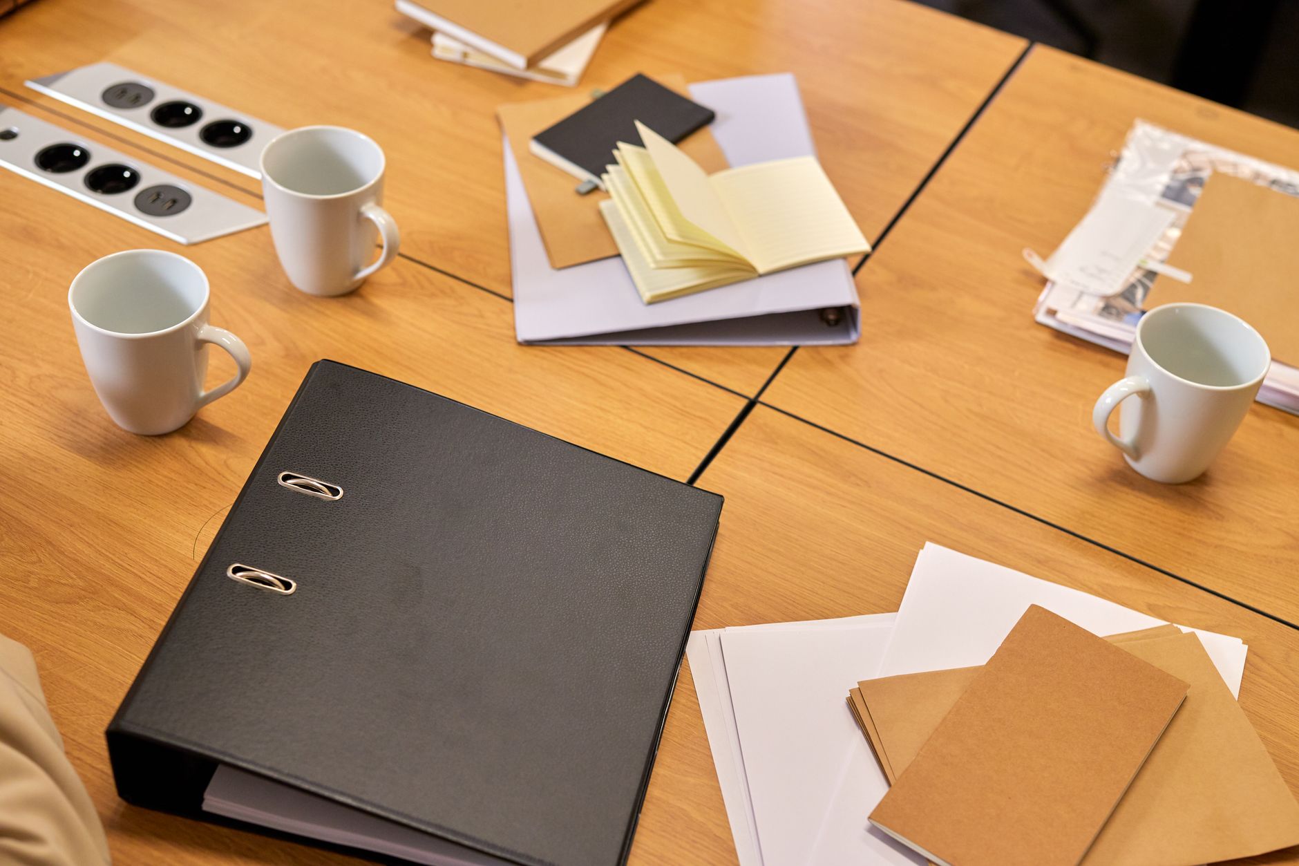 A neat office desk with binders, papers, and coffee mugs arranged neatly,