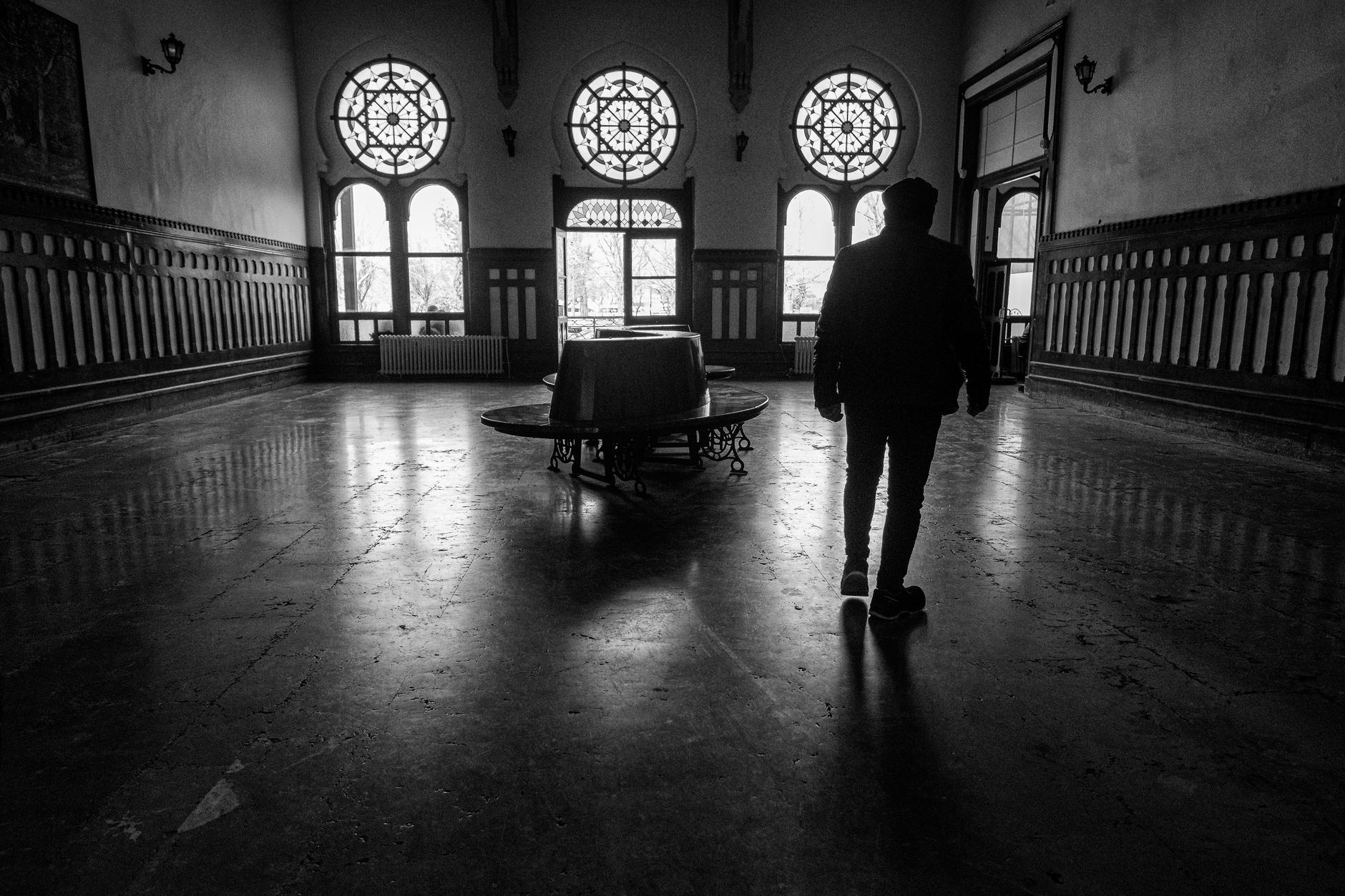A silhouette of a person walking in a grand hallway with stained