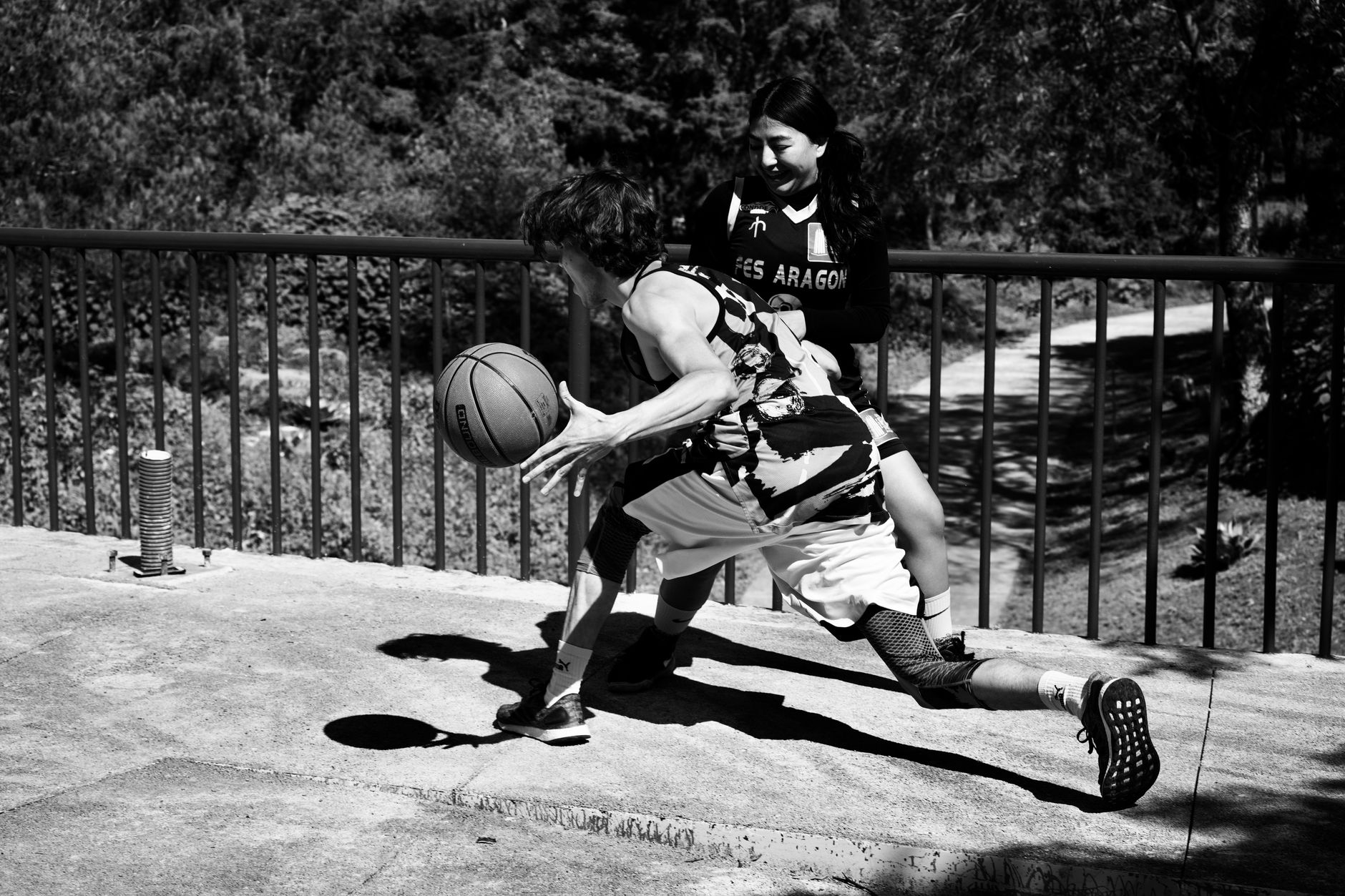 Two players engaged in an intense basketball match on an outdoor court.