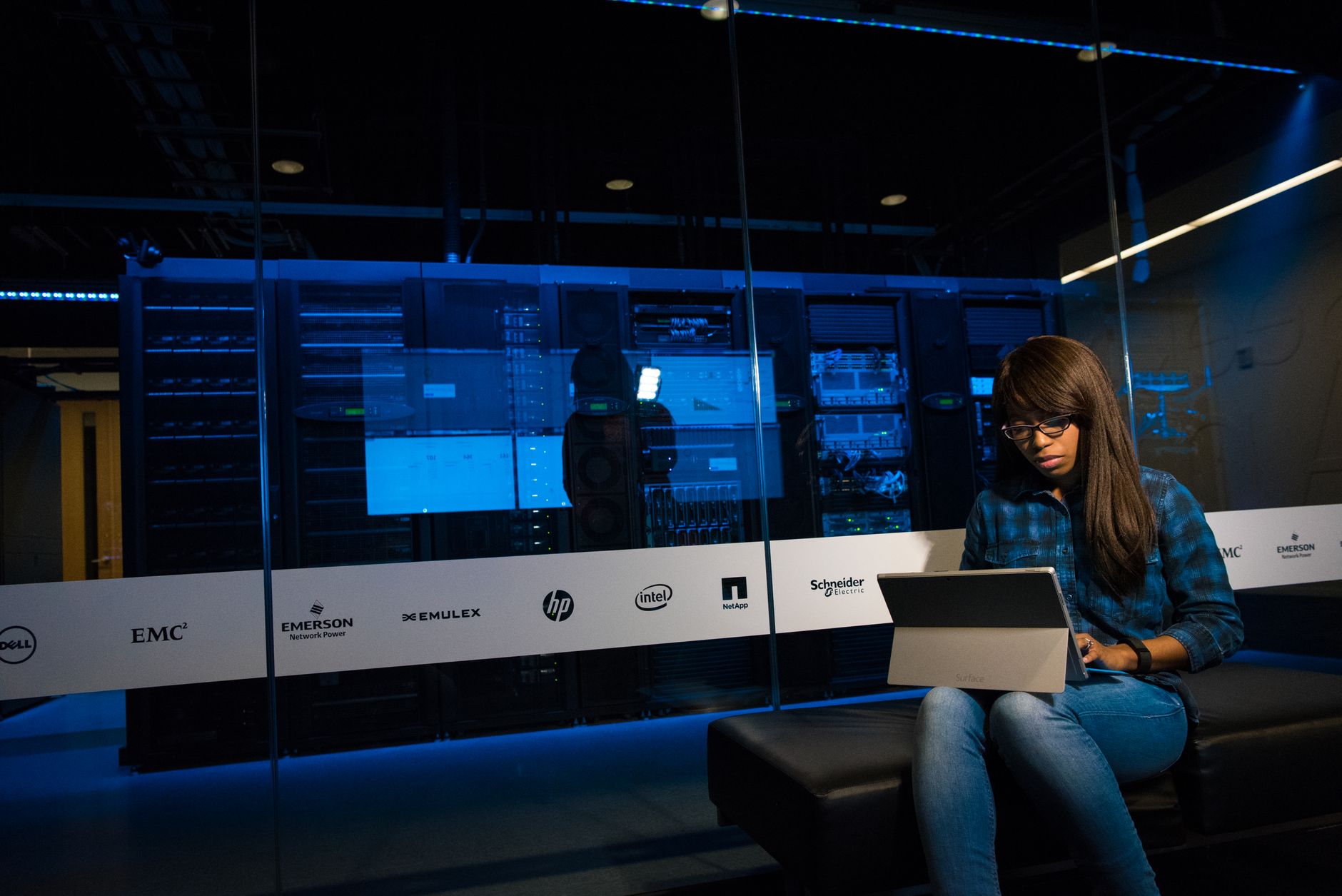 Woman using a laptop in a server room, showcasing modern technology and