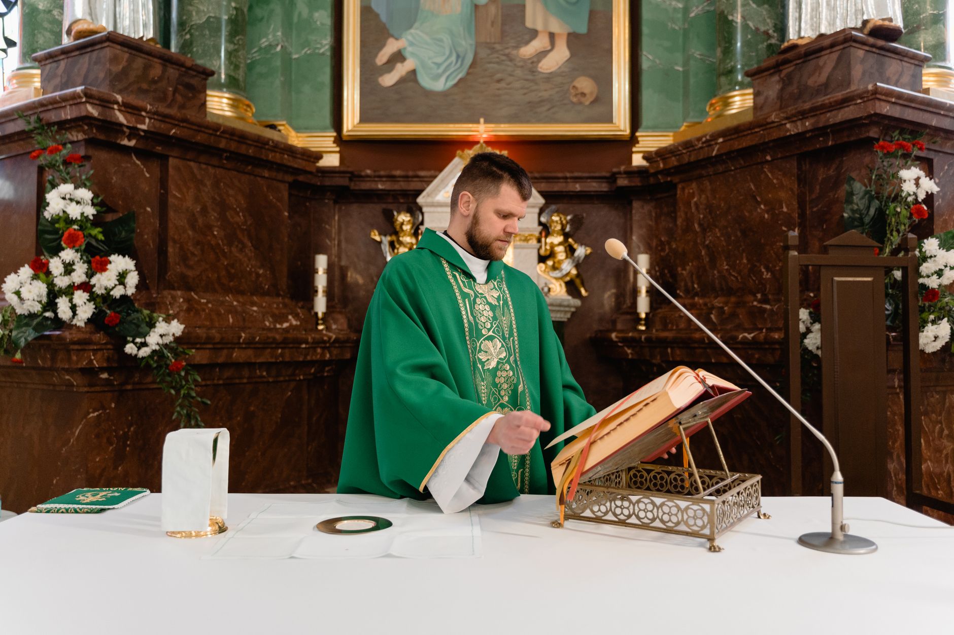 A priest in a green stole reads from a holy book at