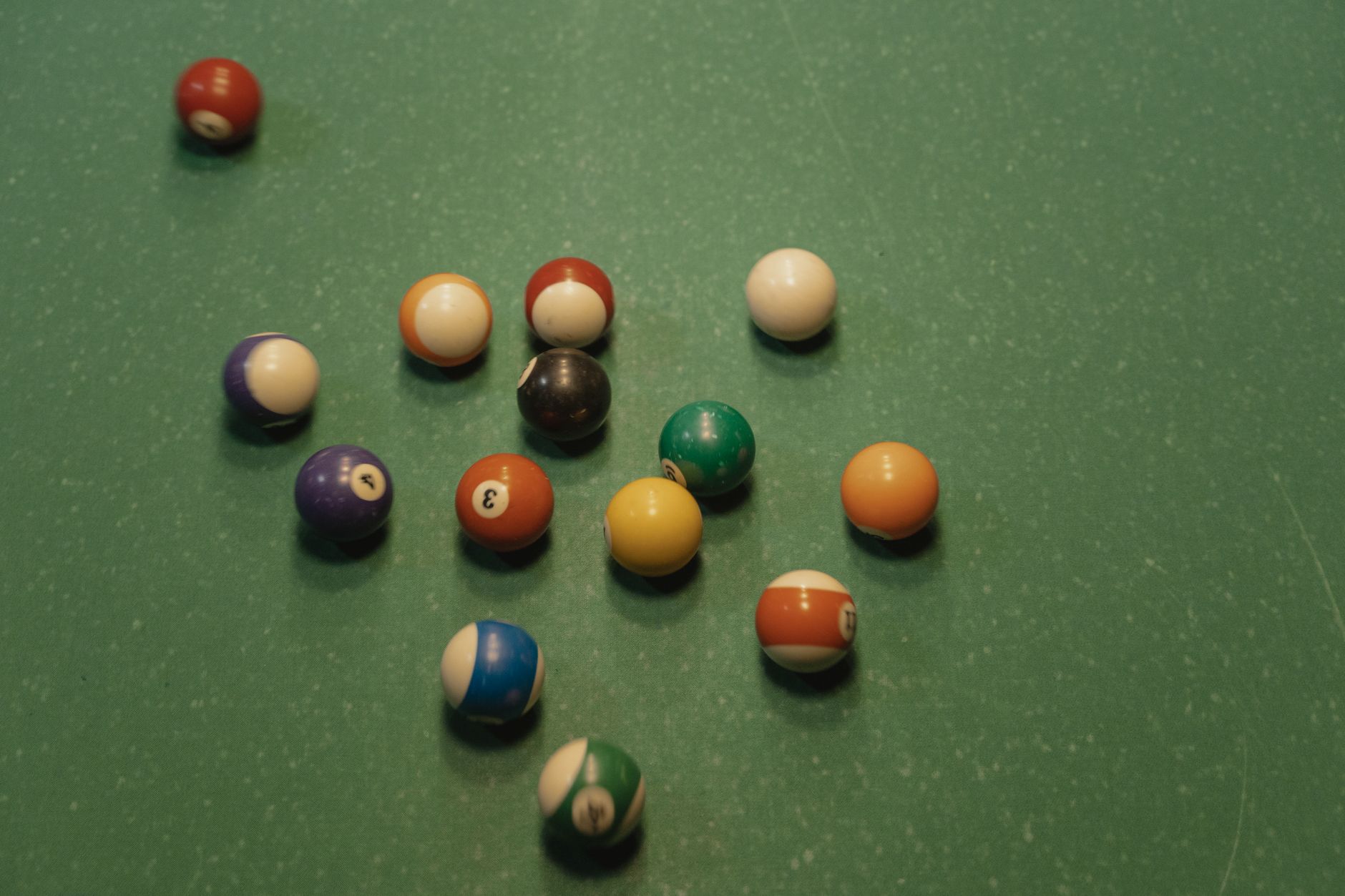 A top view of scattered colorful billiard balls on a pool table,