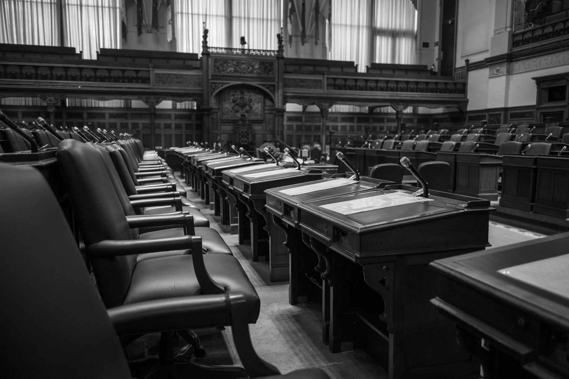 Black and white photo of a traditional legislative assembly chamber, featuring empty
