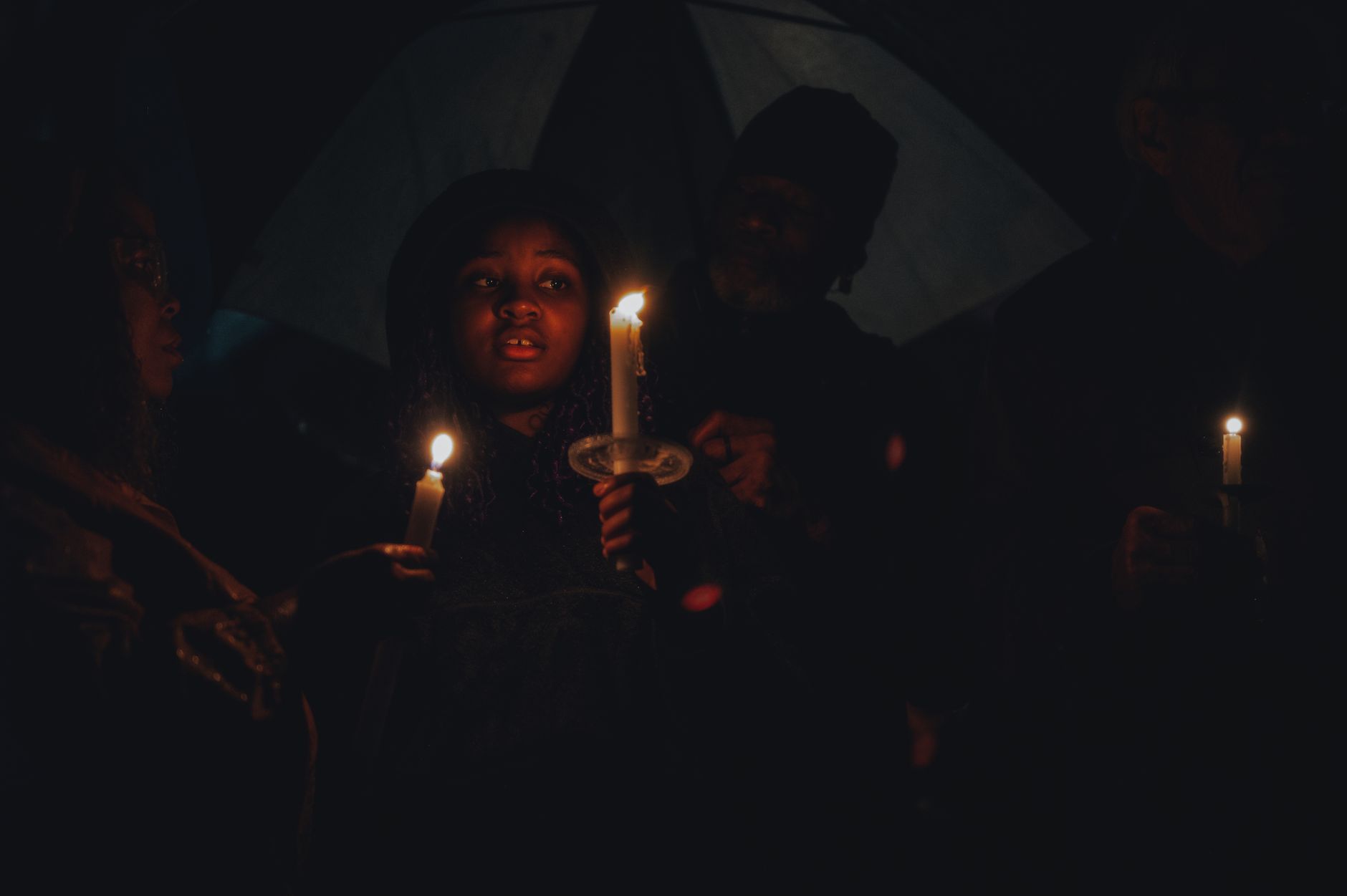 A solemn candlelight vigil attended by diverse individuals, symbolizing unity and peace.