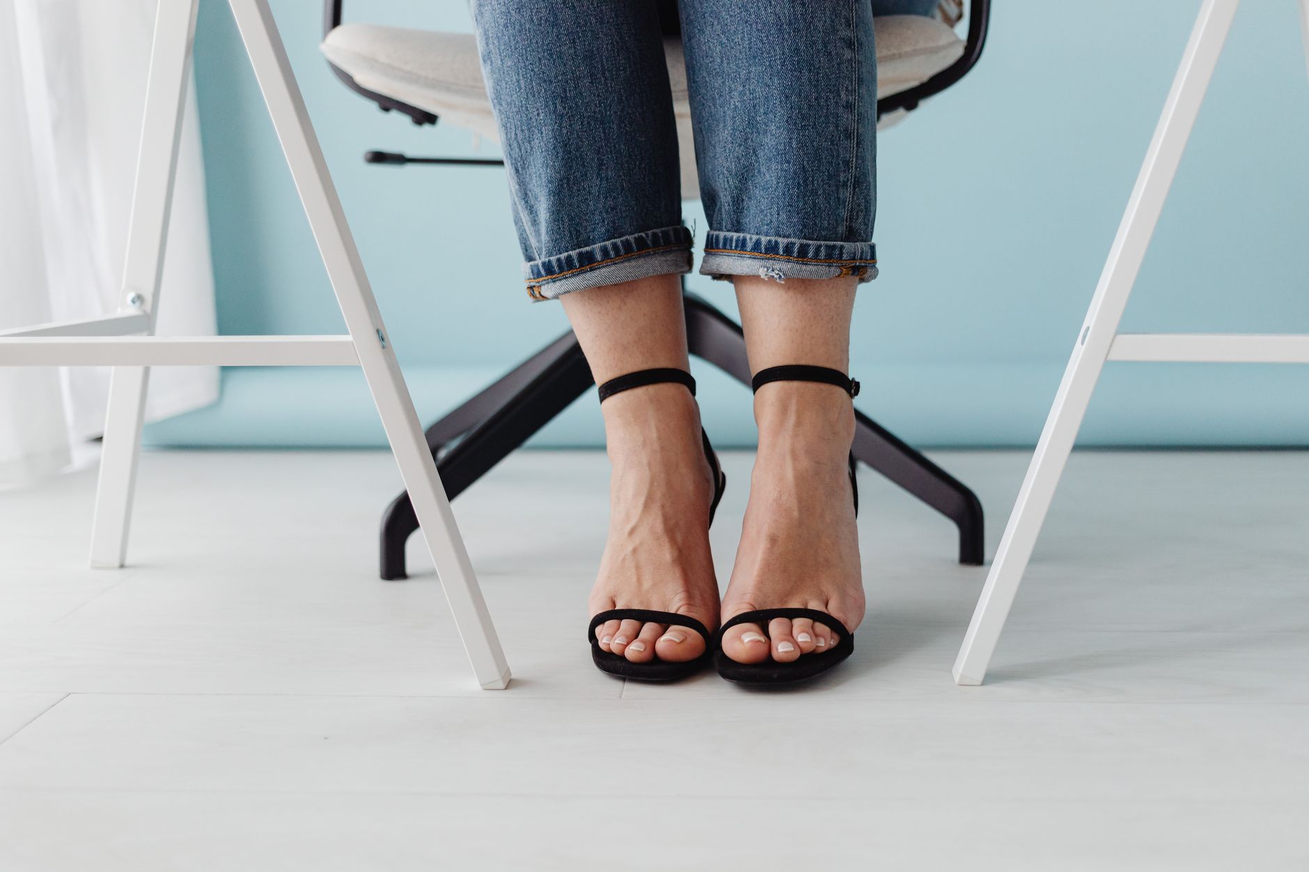 Stylish close-up of a woman wearing black high heels, jeans, and sitting
