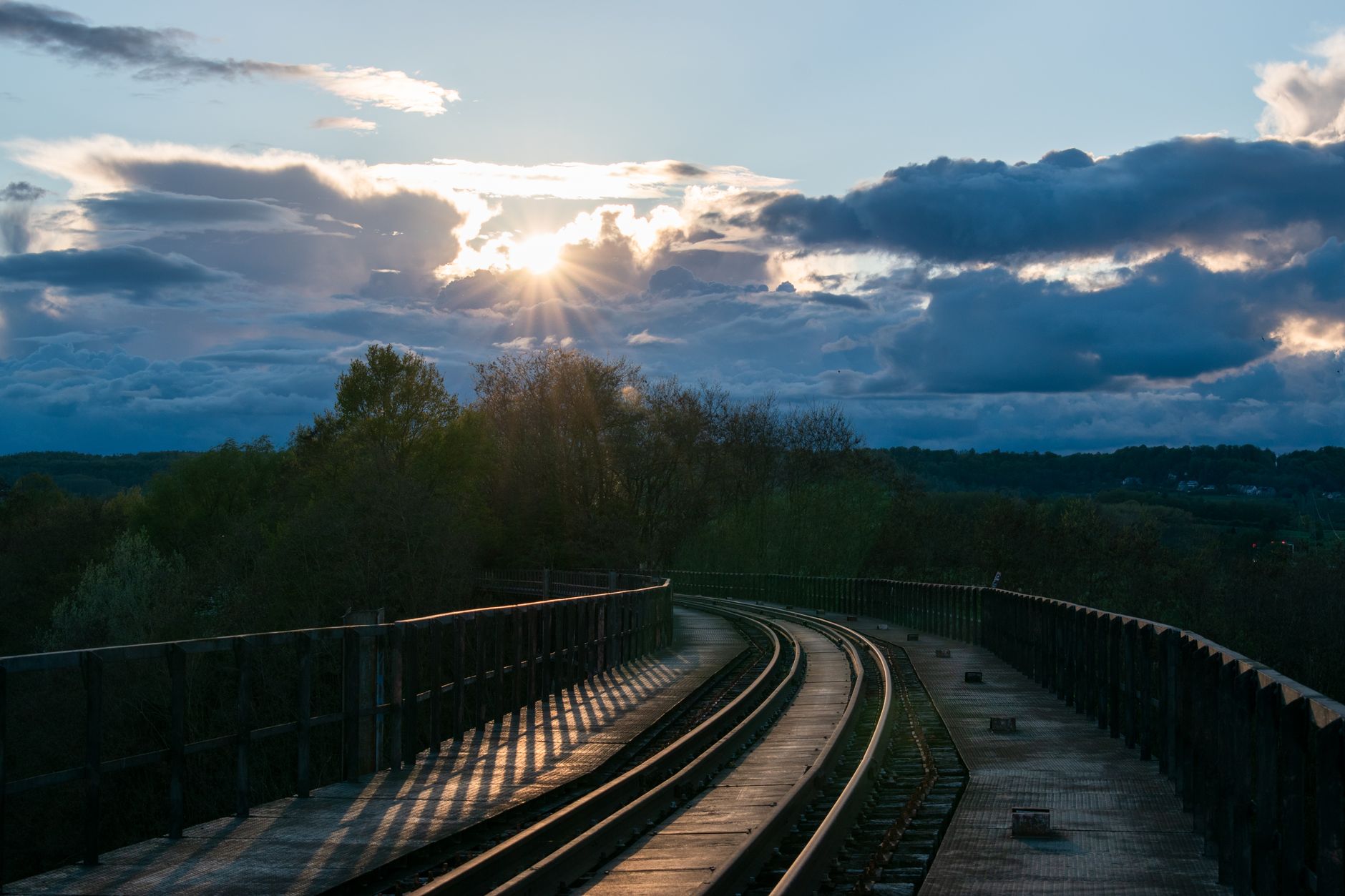 Serene scene of elevated railway tracks under a dramatic sunset sky in