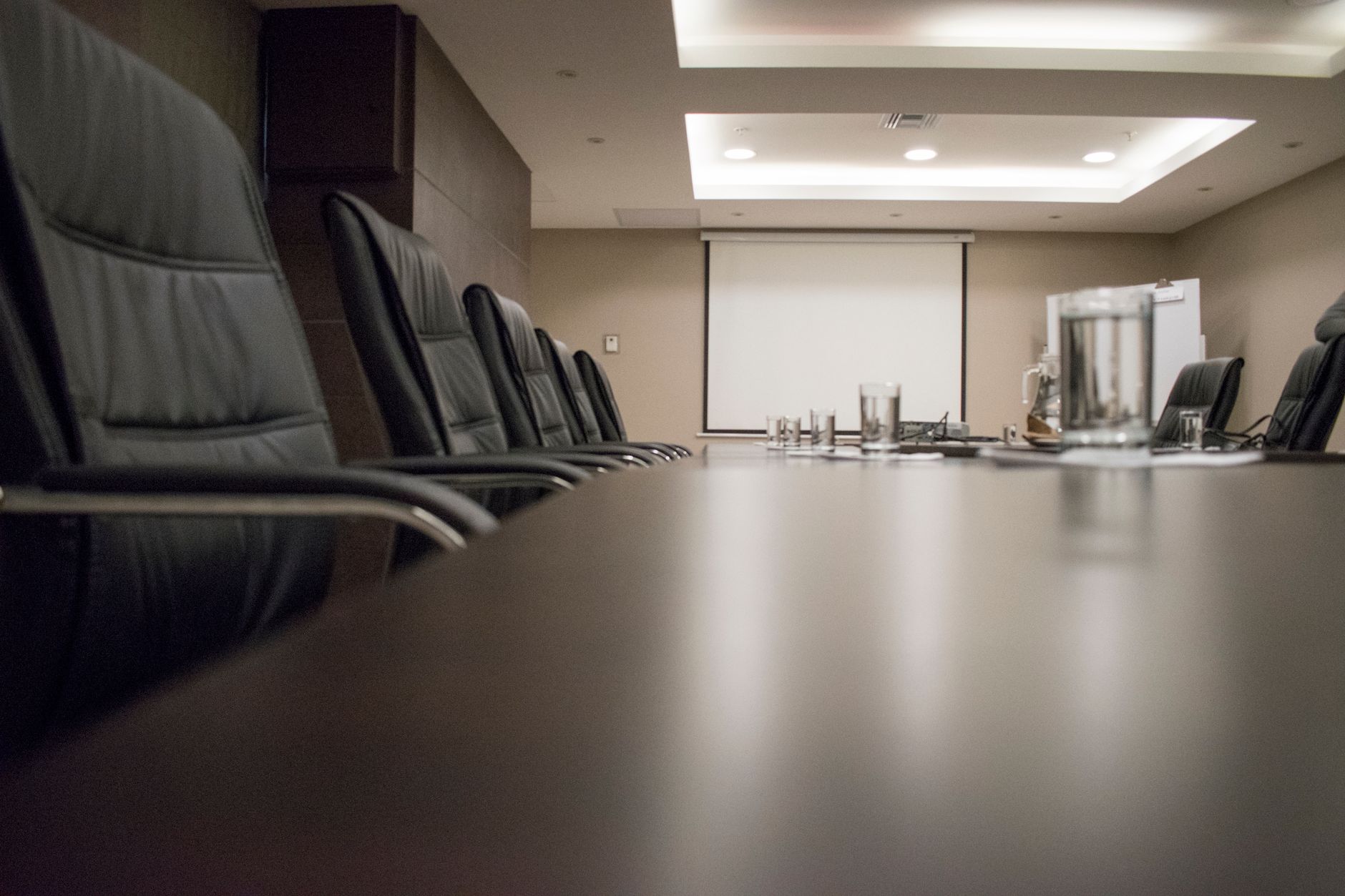 Empty conference room with black chairs, projector, and glasses on table. Ideal