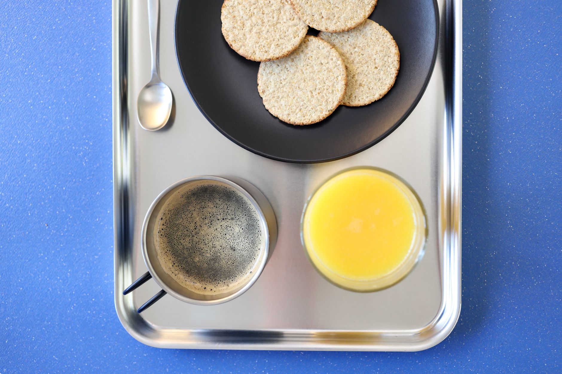 Top-down view of a breakfast tray with coffee, orange juice, and biscuits