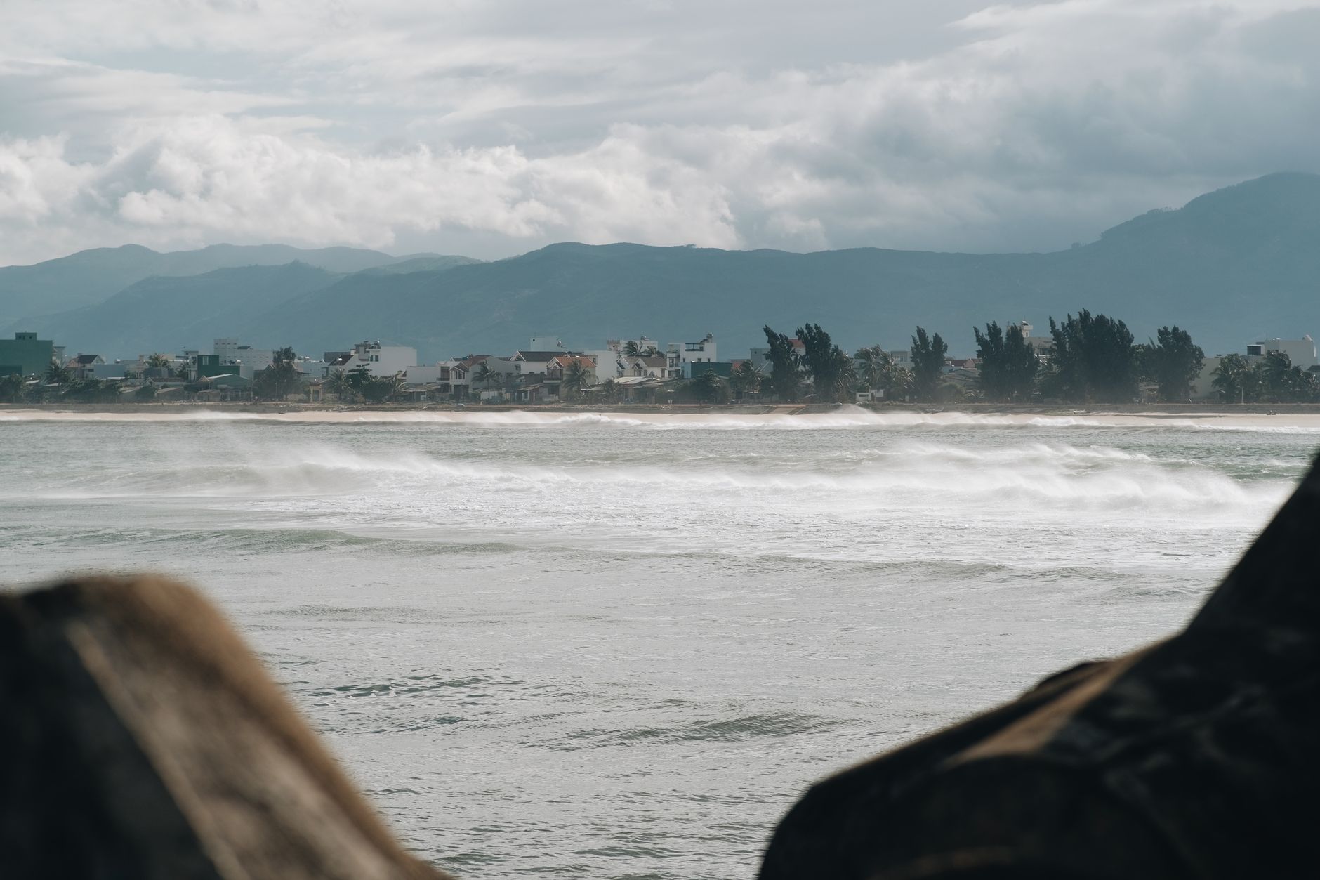 A coastal town with waves crashing against the shore under a stormy