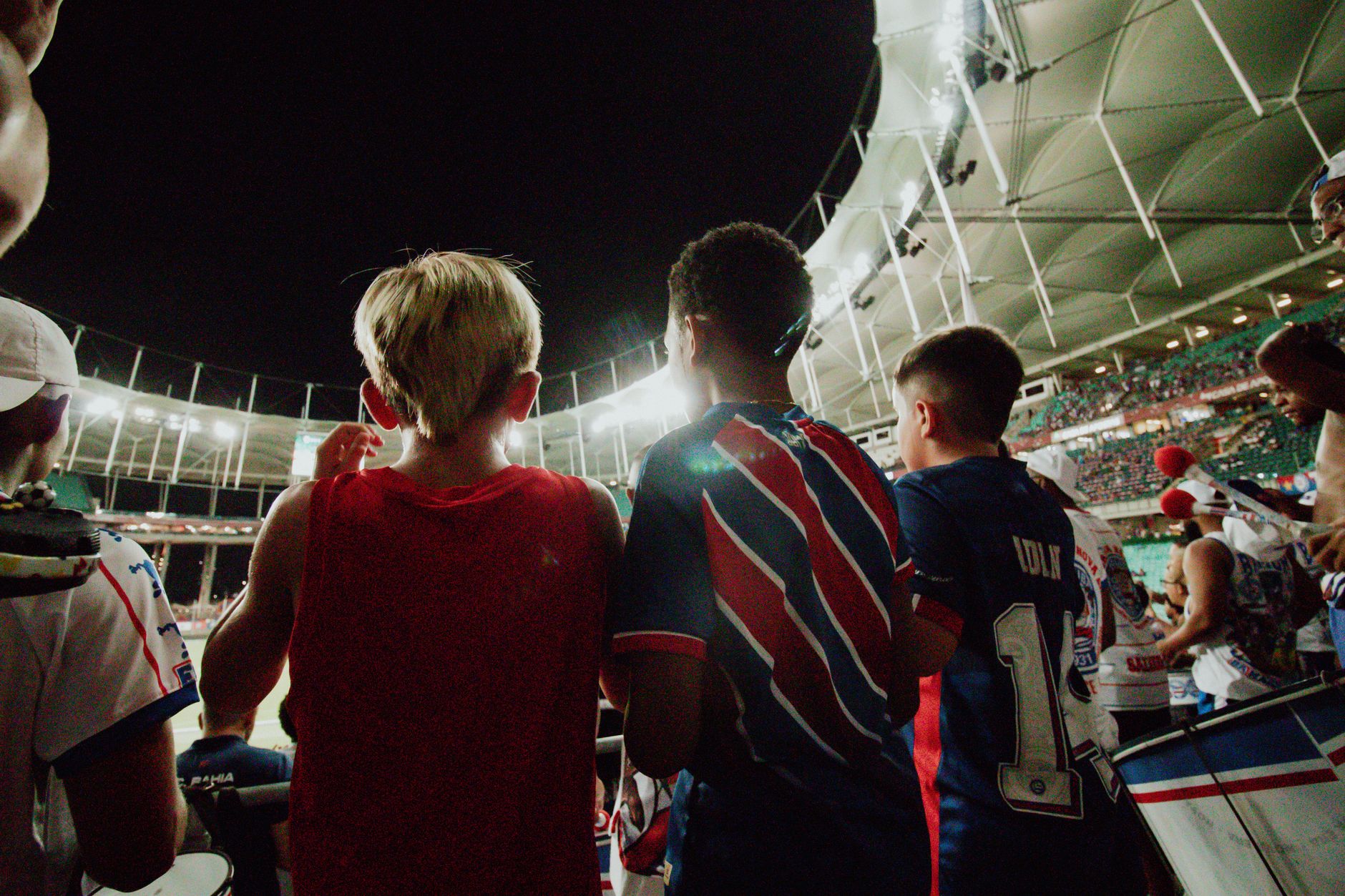 Fans cheer from the stands during a night soccer game in a