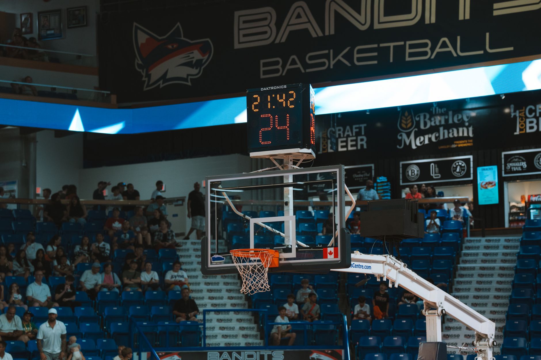 Close-up of a basketball hoop inside a stadium with a scoreboard and