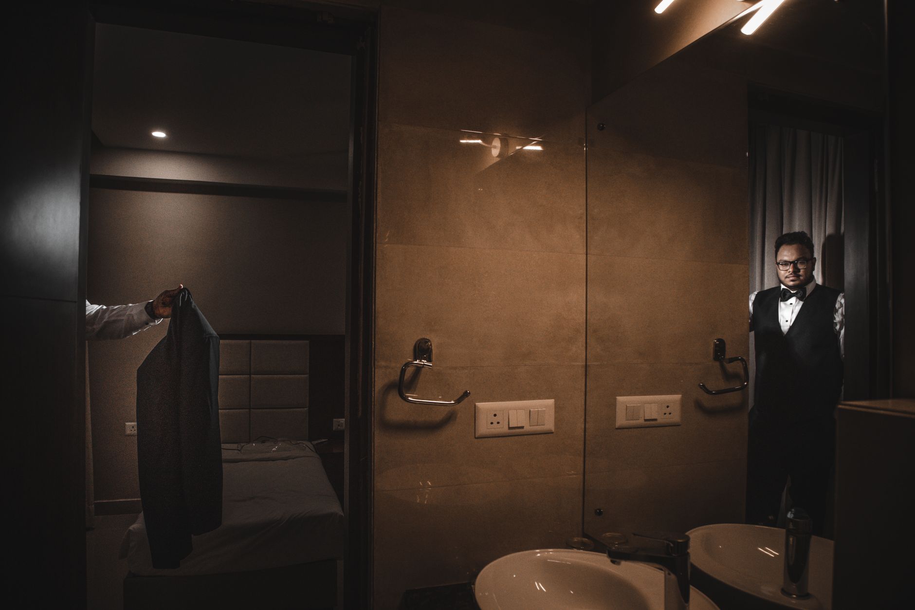 Man in formal suit getting ready in a luxurious hotel suite's dimly lit interior.