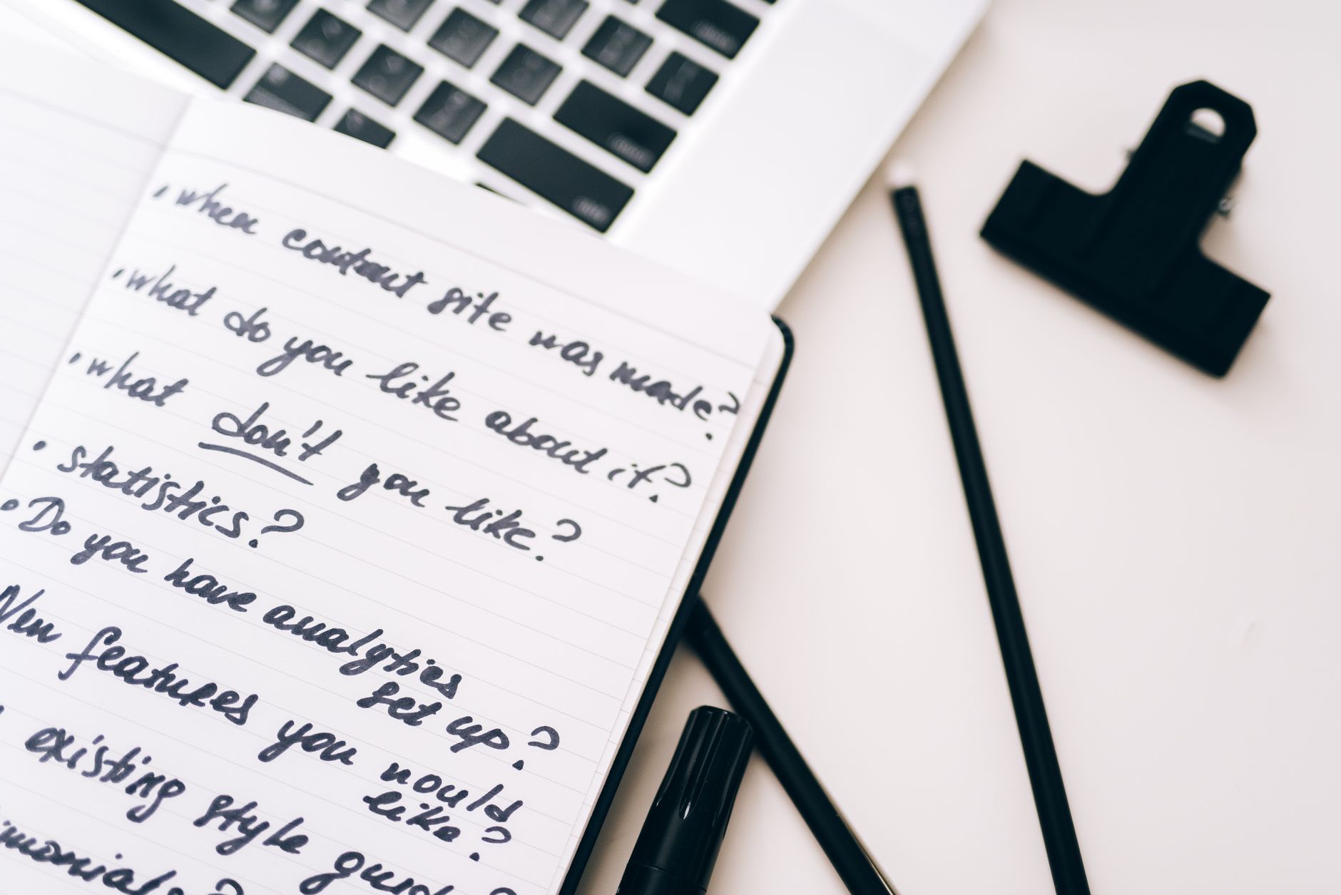 A close-up view of a notebook with handwritten notes alongside a laptop