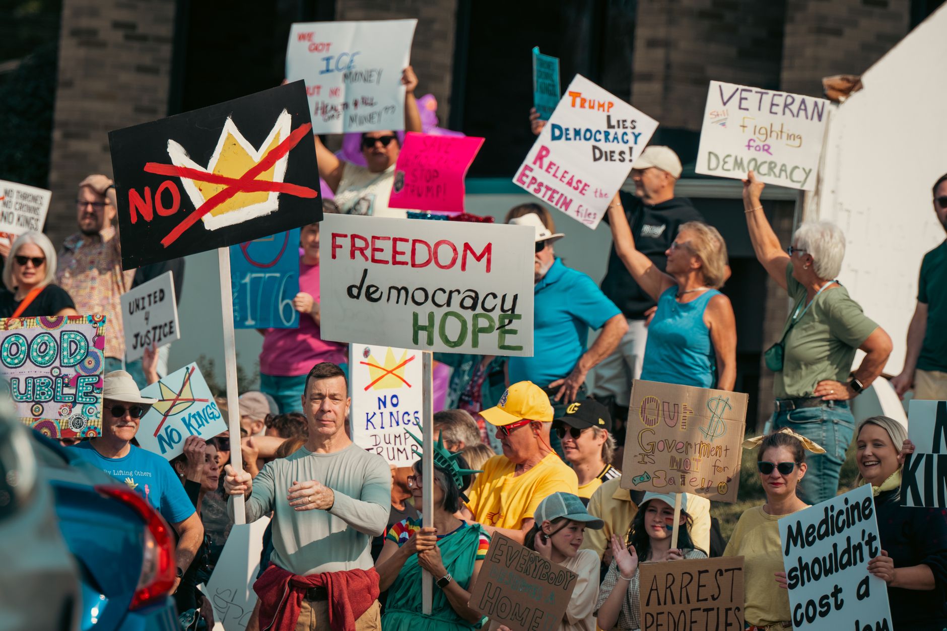 A diverse group of protesters holds signs advocating for freedom and democracy