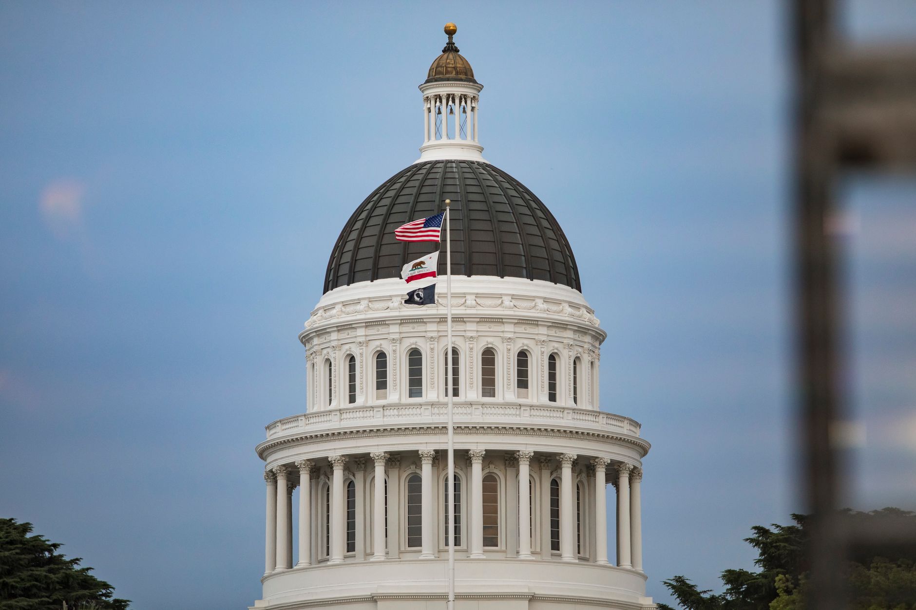 View of California State Capitol dome with American and state flags.