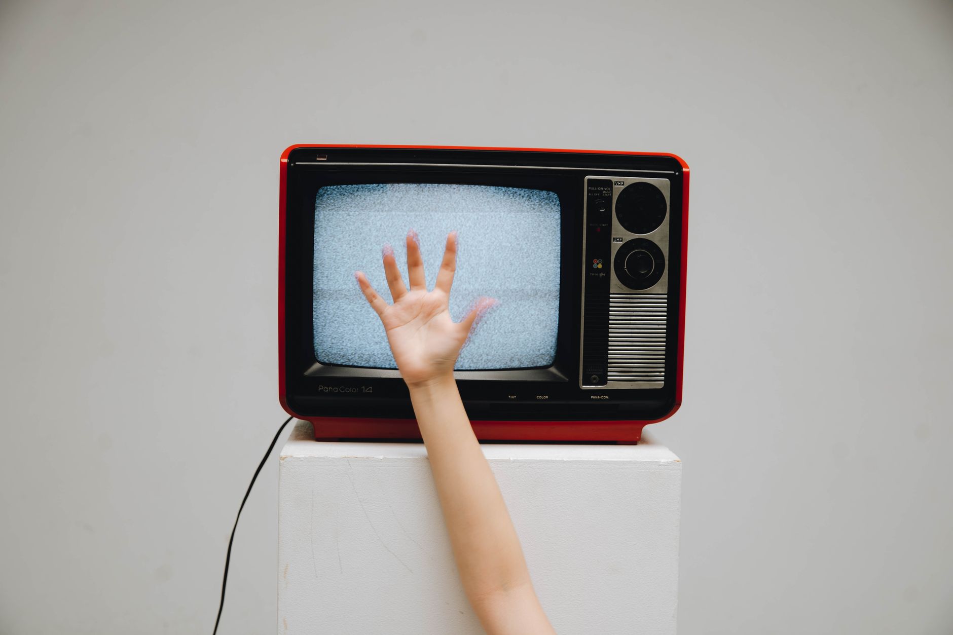 A classic retro television displaying static with a hand reaching towards the