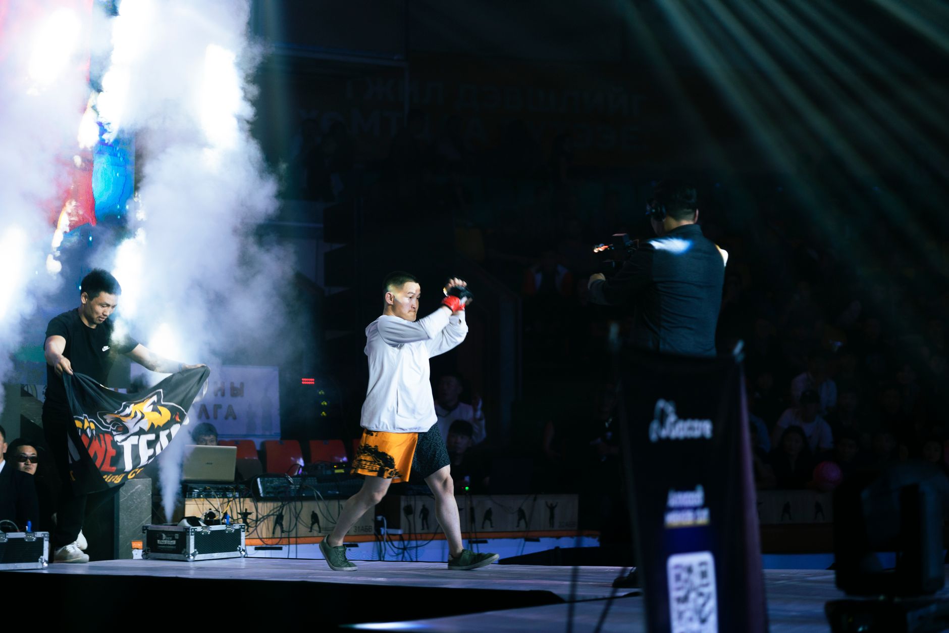 Exciting entrance of an MMA fighter amidst smoke and lights in the