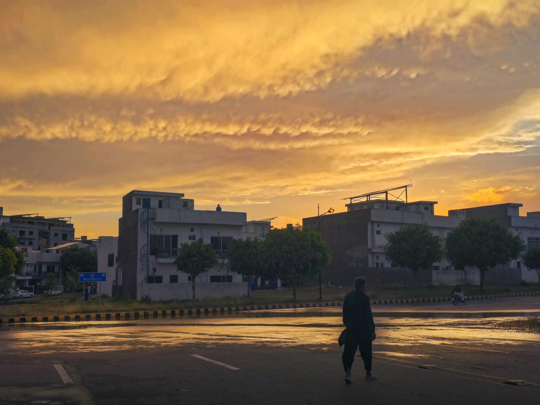 A silhouette of a person walking on a wet street under a
