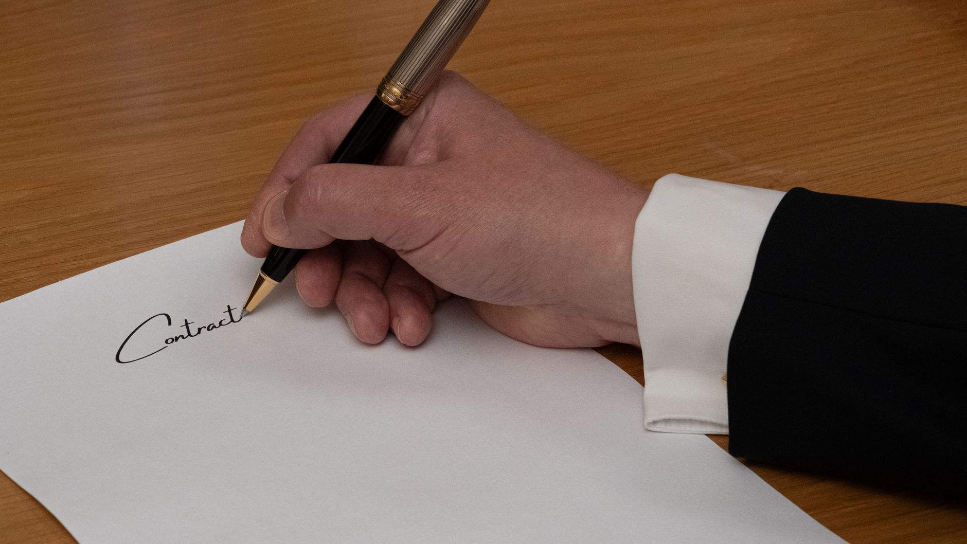 A professional signing a business contract with a fountain pen on a