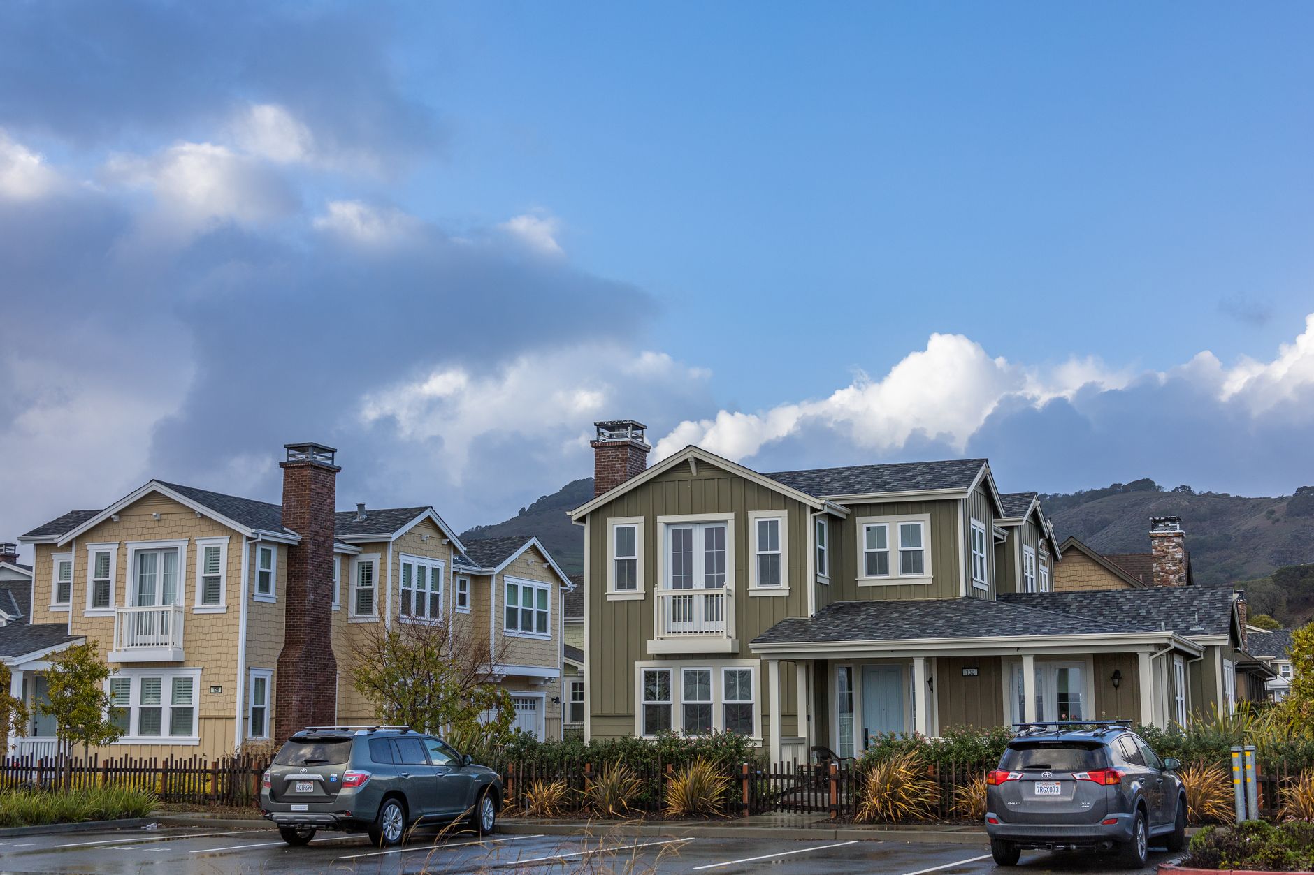 Picturesque suburban neighborhood with modern houses and parked cars under a partly