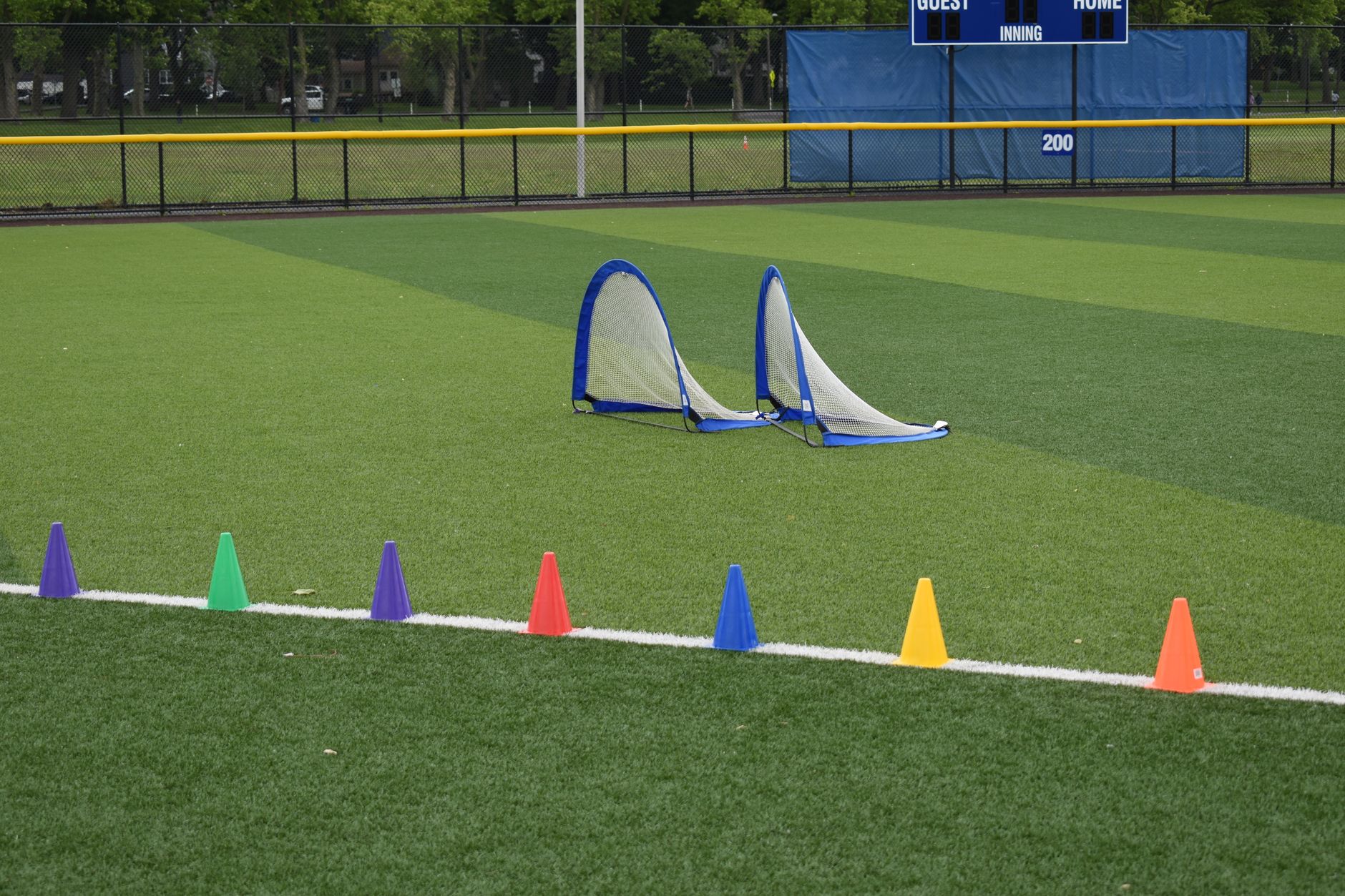 Colorful training cones and soccer nets on an empty sports field.