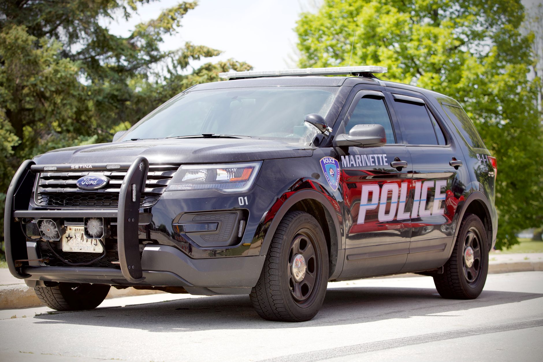 A black Marinette police SUV parked outdoors on a sunny day.