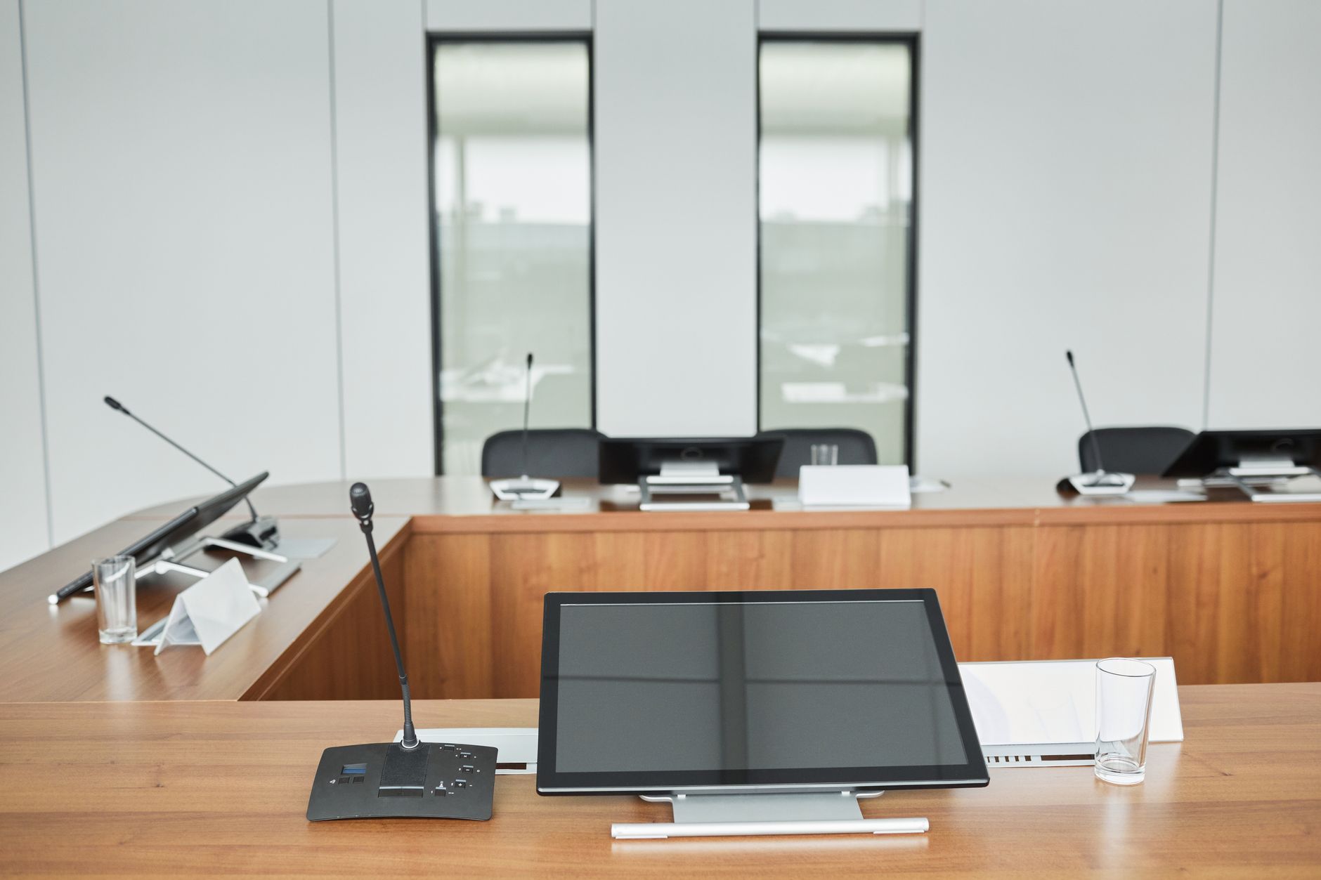 Empty conference room setup with microphones, monitors, and sleek wooden tables ready