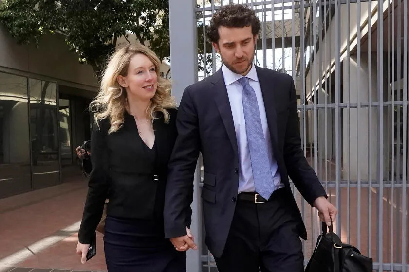 Elizabeth Holmes and Billy Evans walk hand in hand.