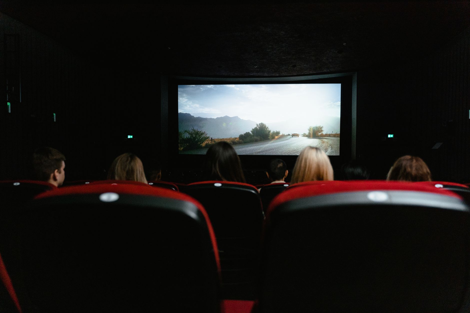 View from behind of people watching a movie in a cinema with