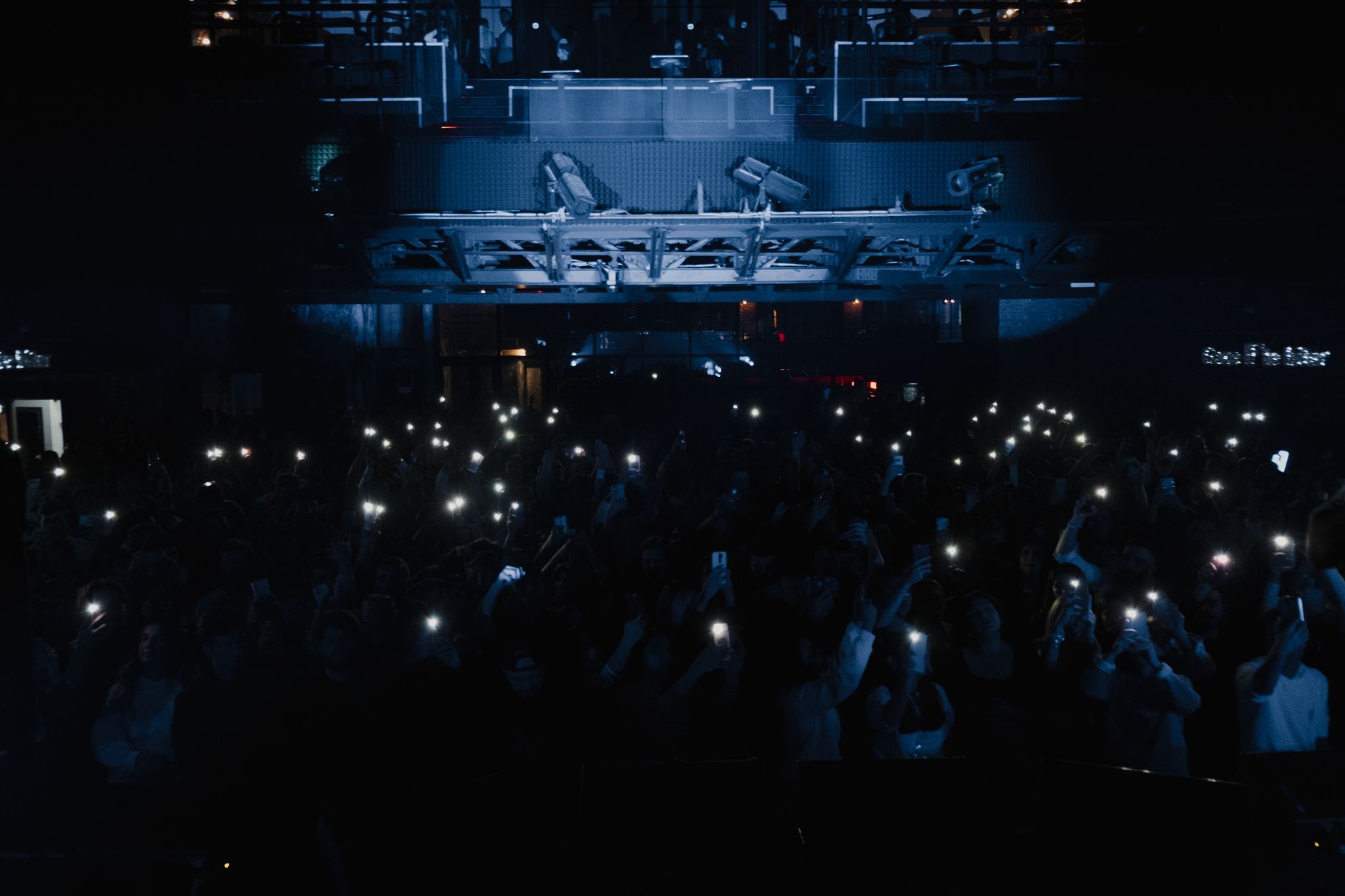 A lively concert scene with a crowd holding up smart phones and